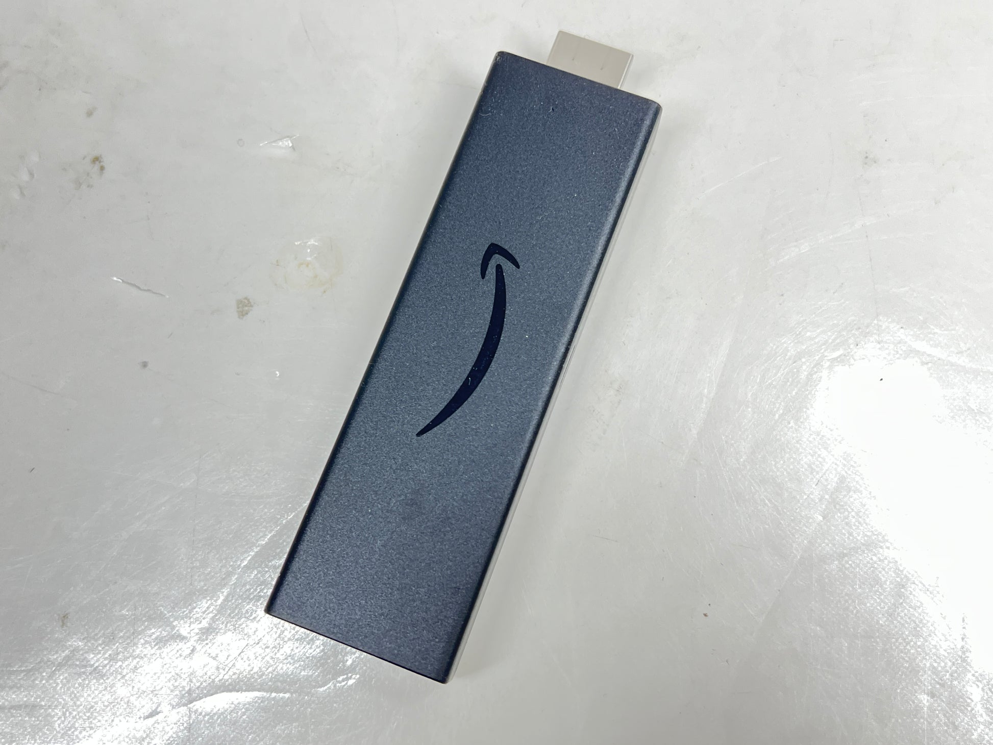 Dark blue Amazon Fire TV Stick with HDMI plug and Amazon smile logo shown from multiple angles