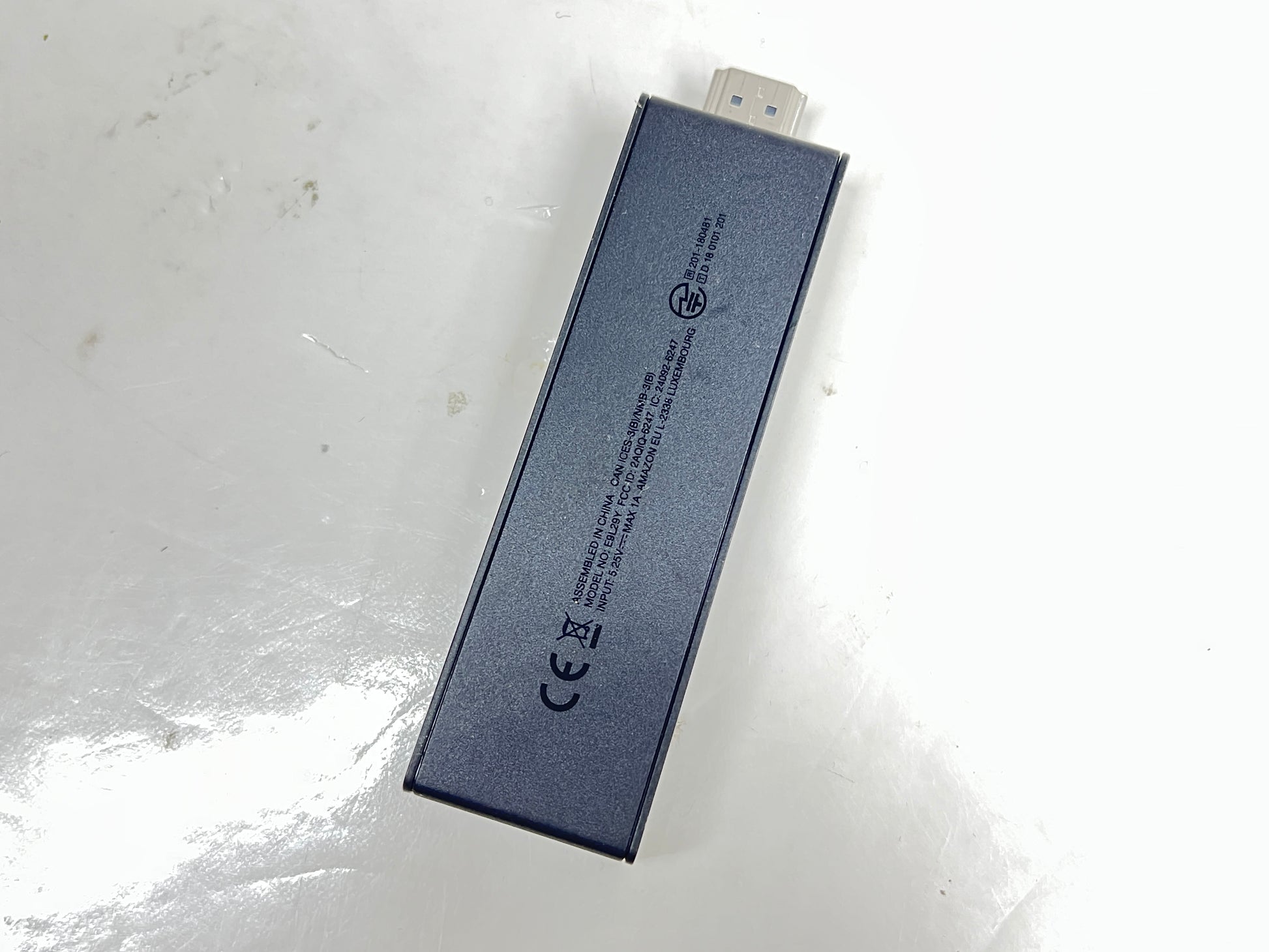 Dark blue Amazon Fire TV Stick with HDMI plug and Amazon smile logo shown from multiple angles