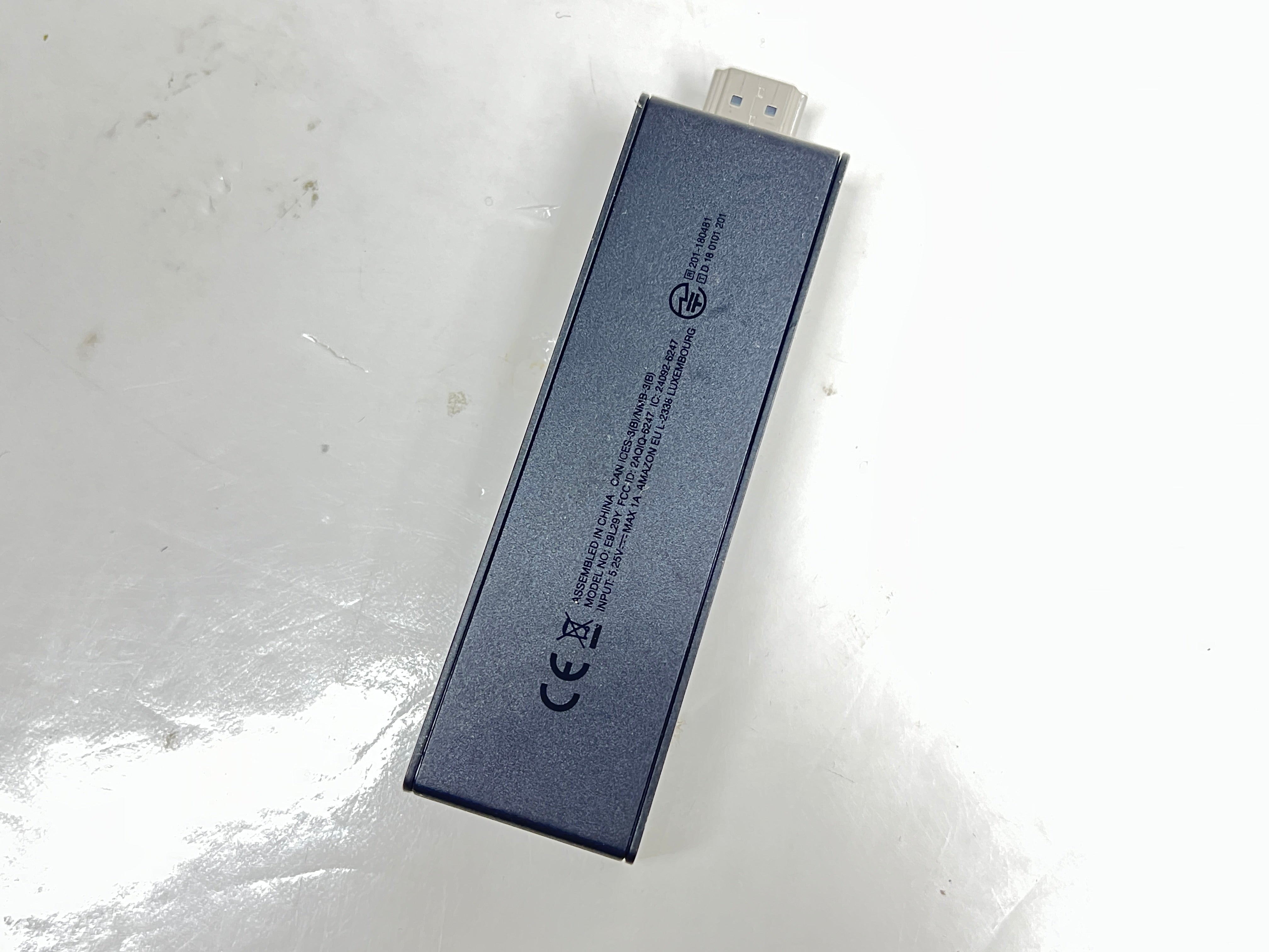 Dark blue Amazon Fire TV Stick with HDMI plug and Amazon smile logo shown from multiple angles