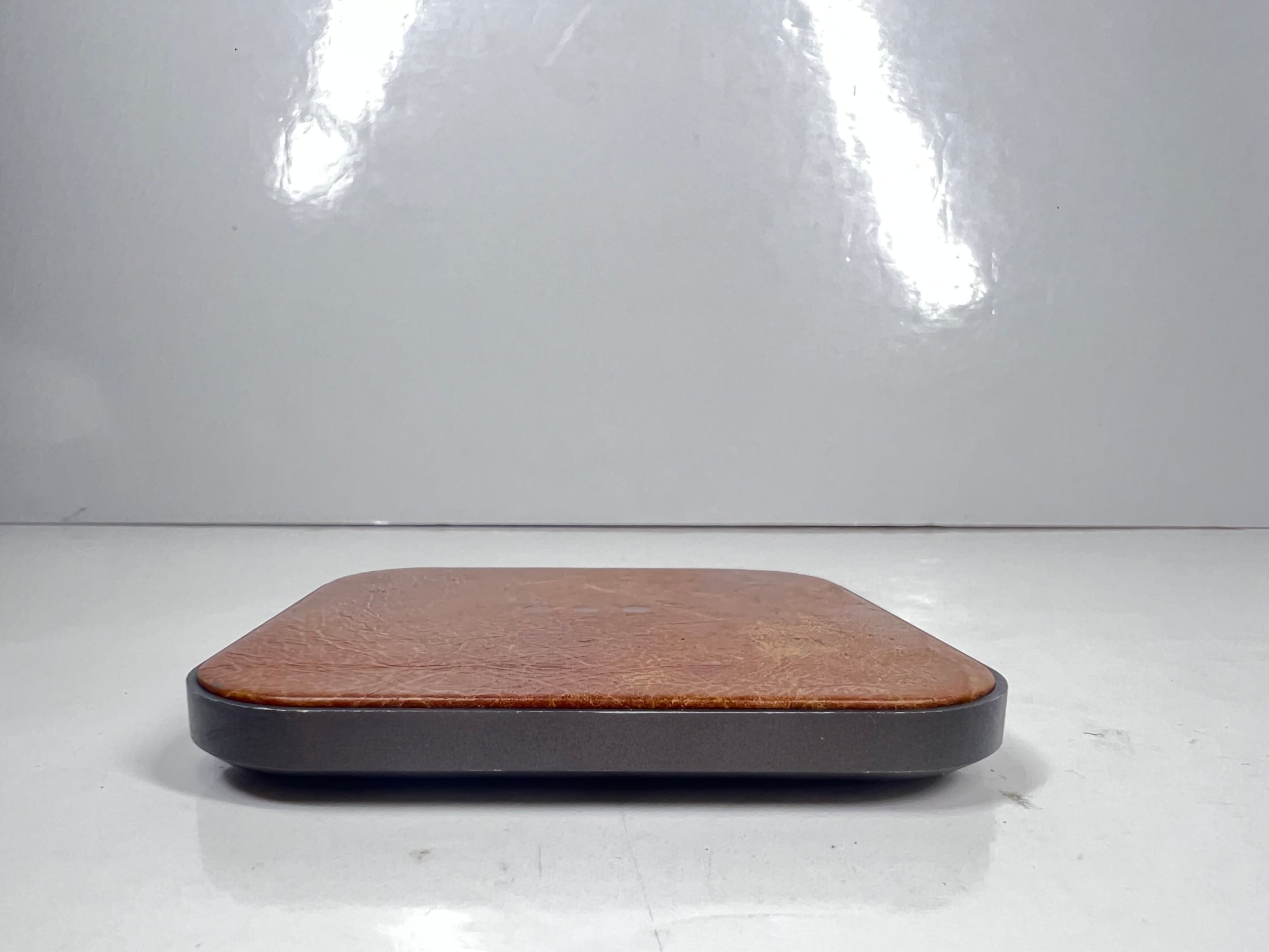 Leather-top Courant wireless charging pad with USB-C input, brown with visible wear and LED indicator dots.