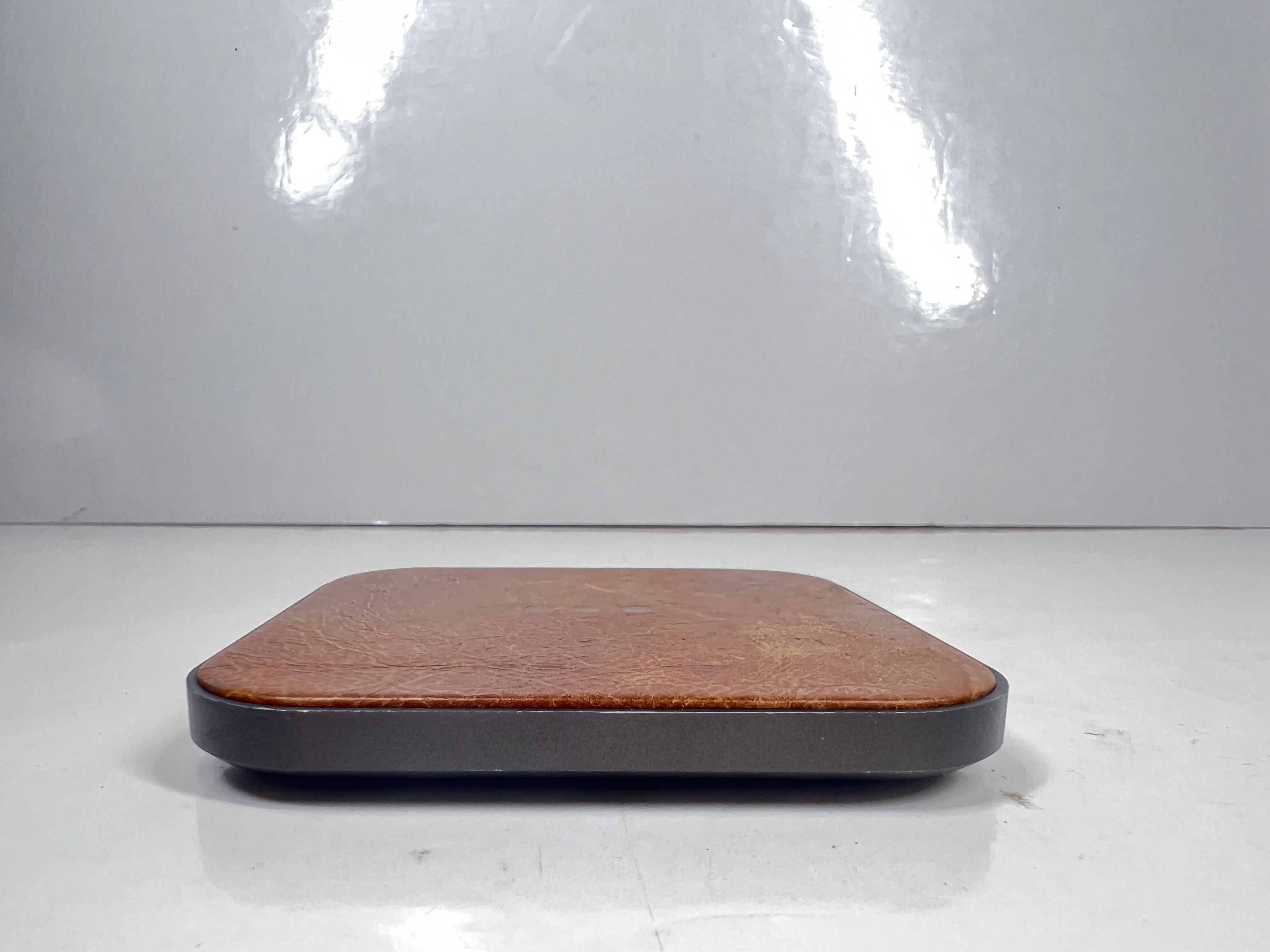 Leather-top Courant wireless charging pad with USB-C input, brown with visible wear and LED indicator dots.