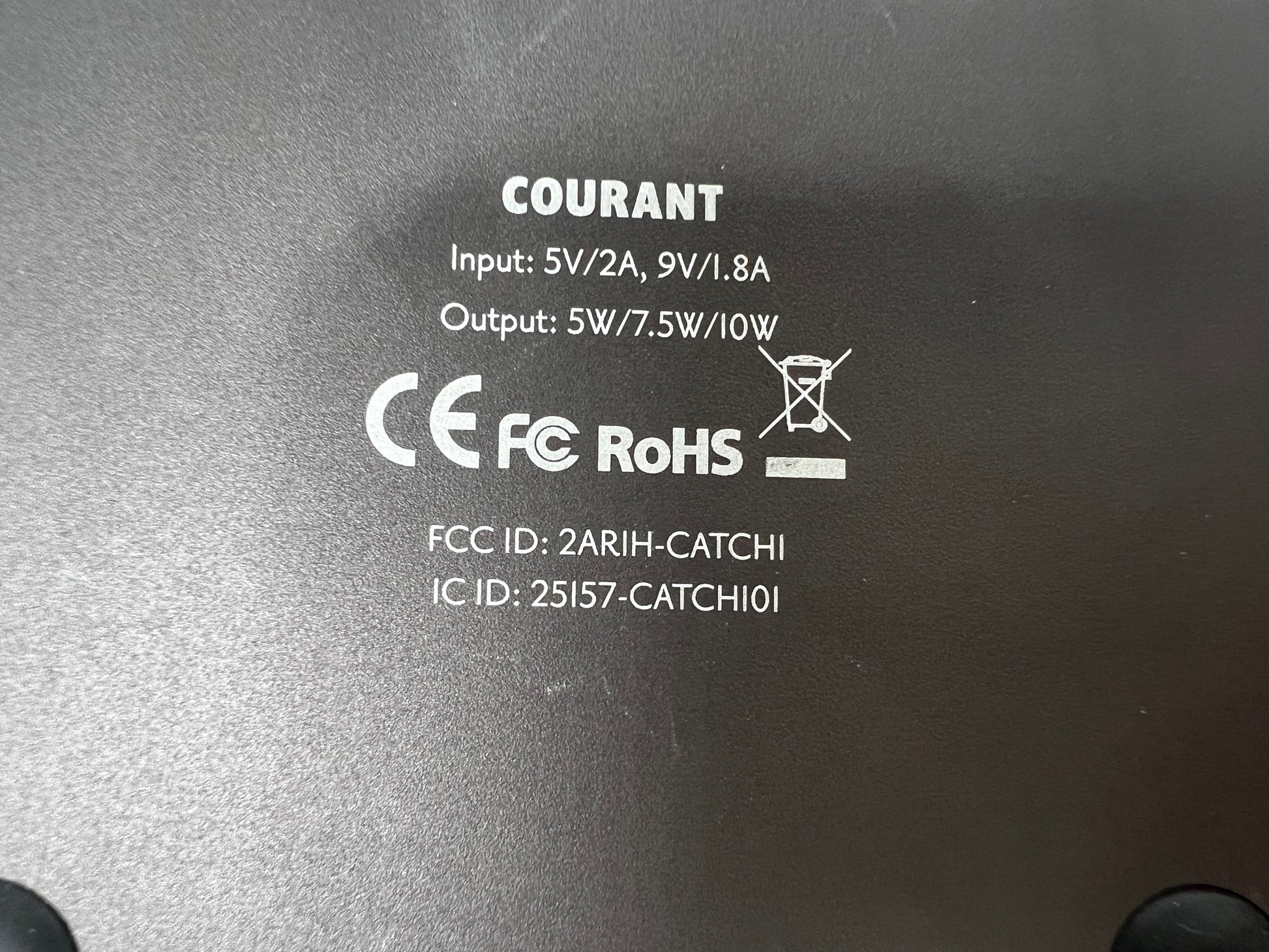 Leather-top Courant wireless charging pad with USB-C input, brown with visible wear and LED indicator dots.
