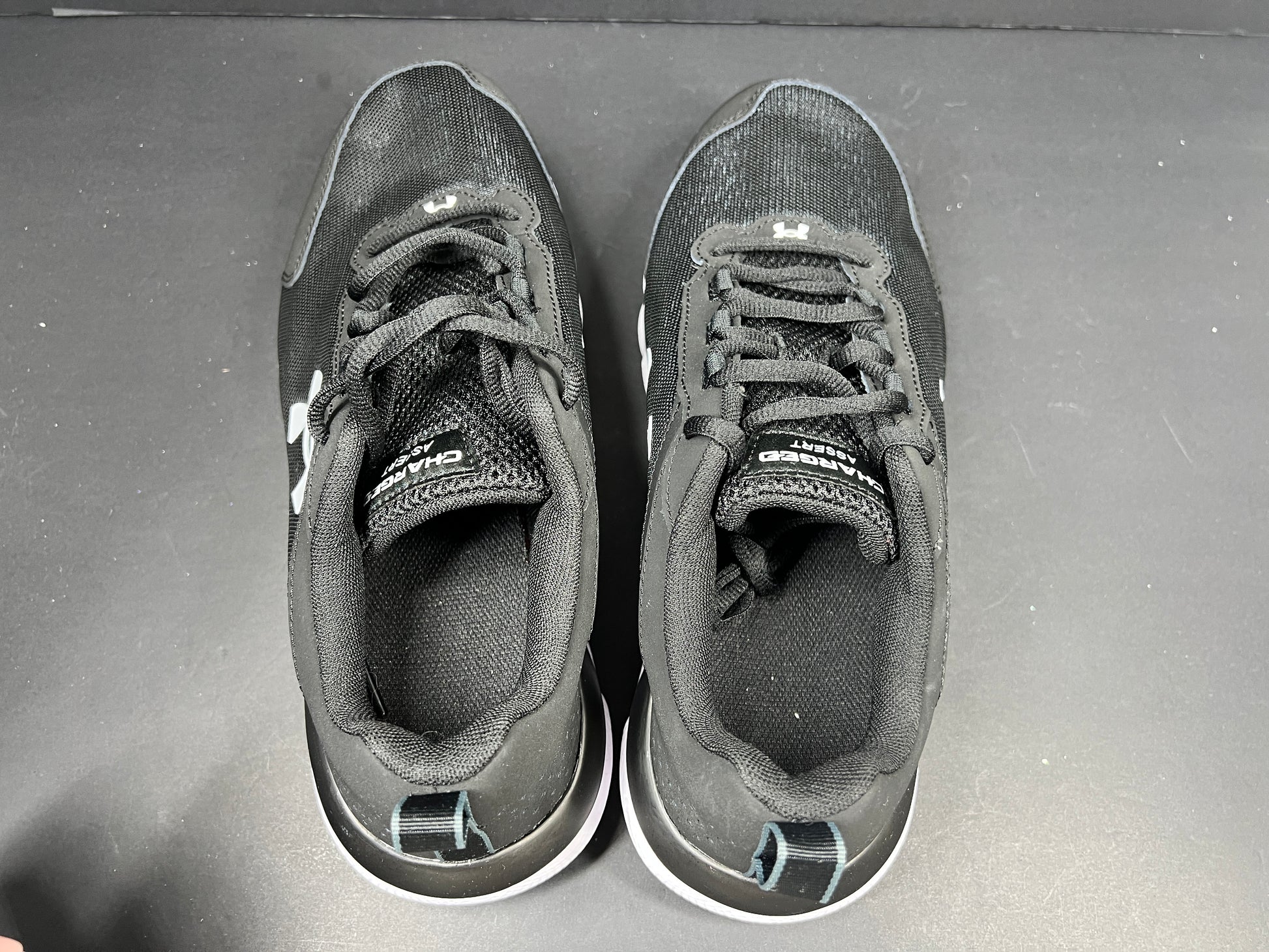 A pair of black Under Armour Charged Assert 9 running shoes for men