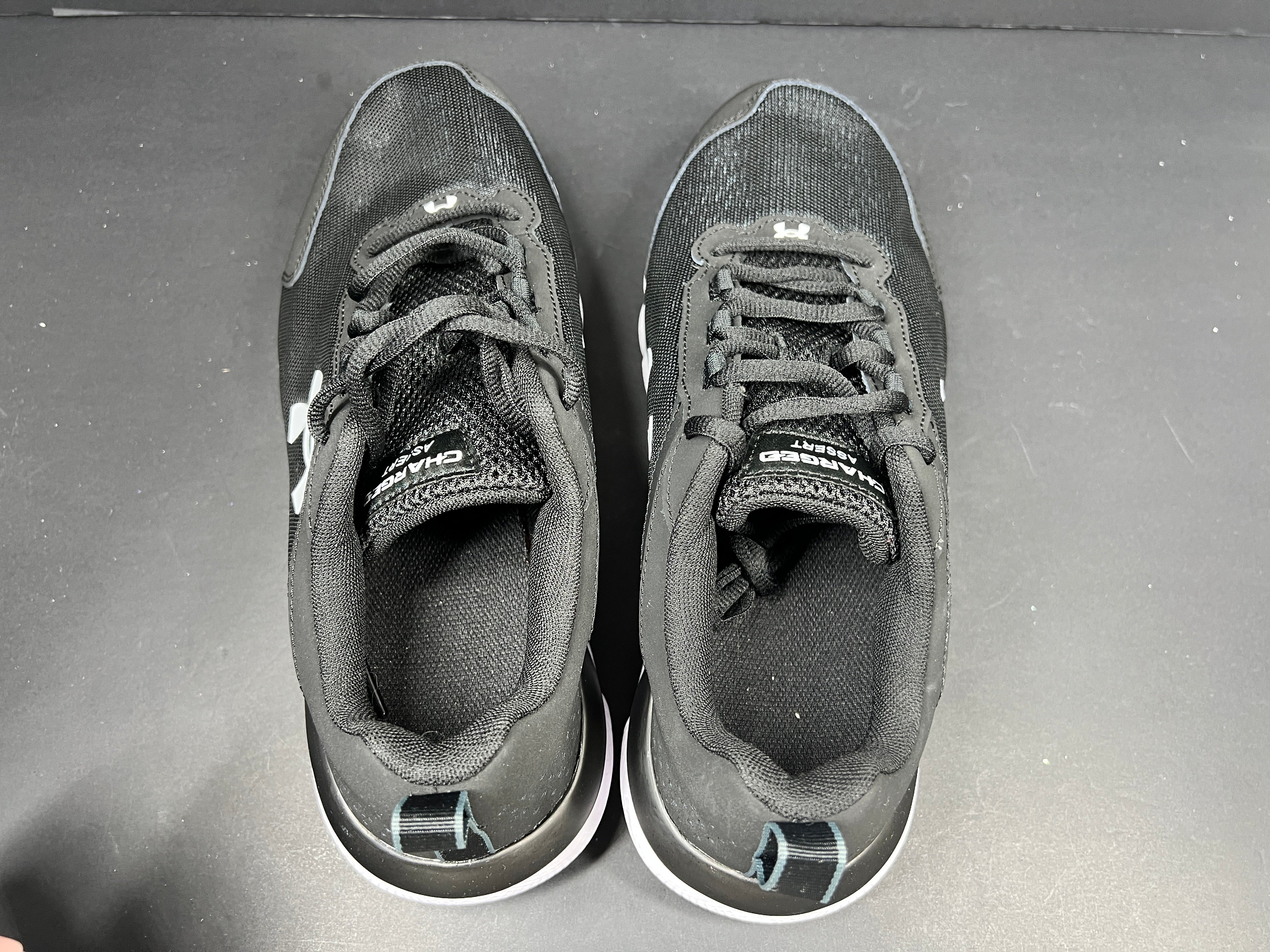 A pair of black Under Armour Charged Assert 9 running shoes for men