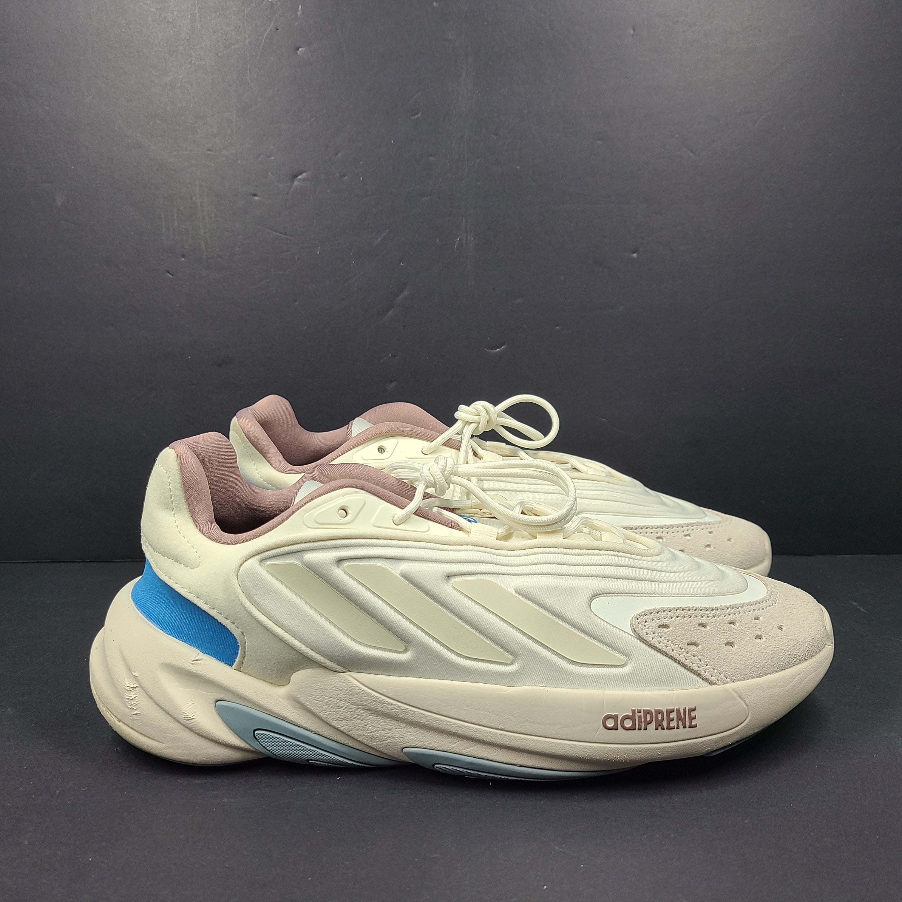 A pair of cream and blue Adidas adiPRENE sneakers in size 9.5 for men.