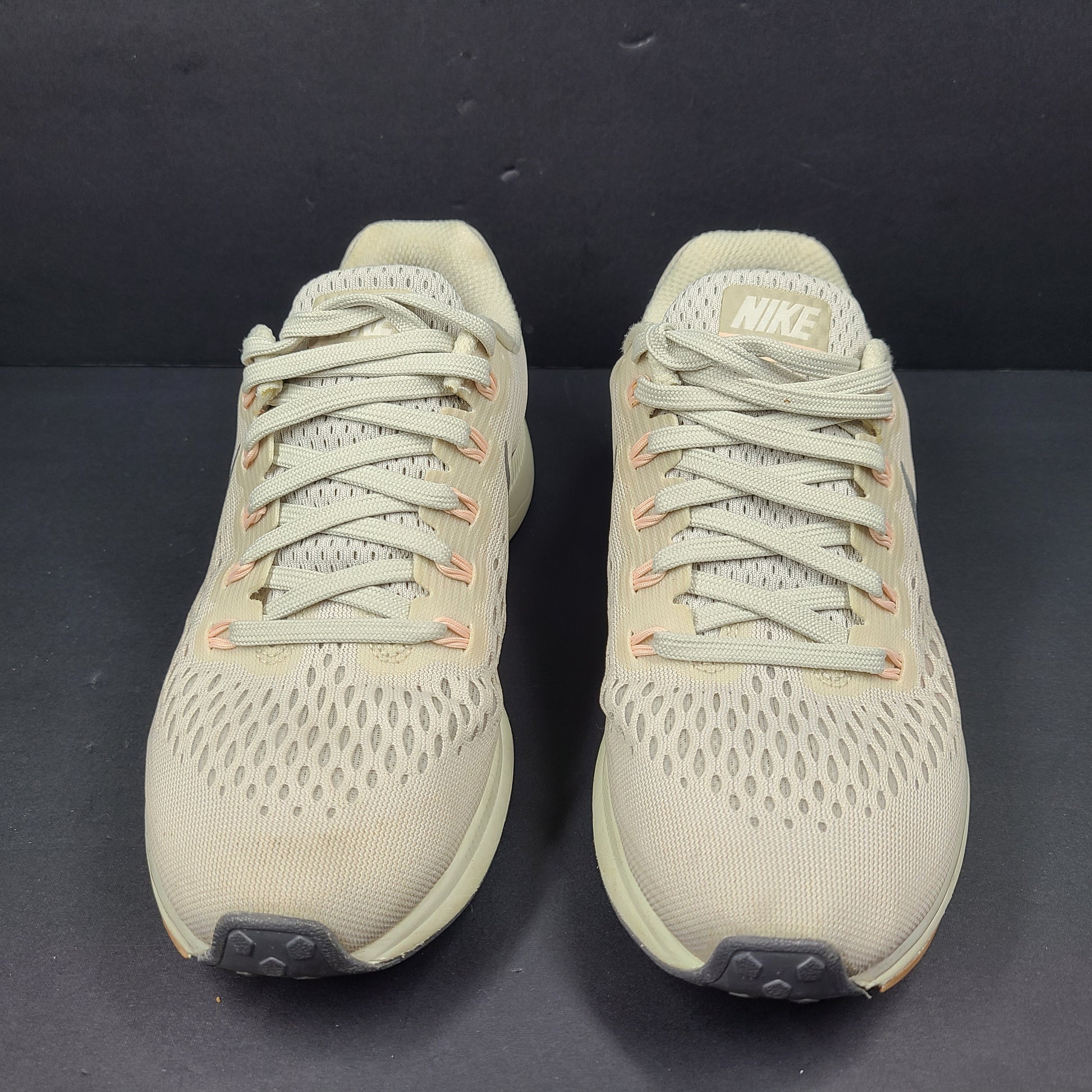 A pair of beige Nike Zoom running shoes.