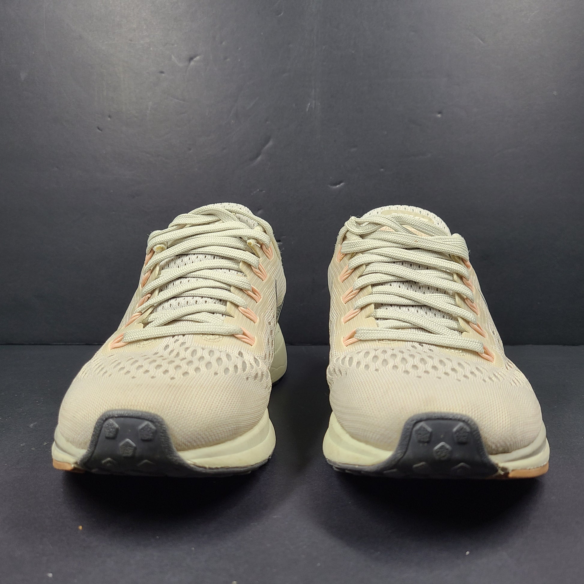 A pair of beige Nike Zoom running shoes.