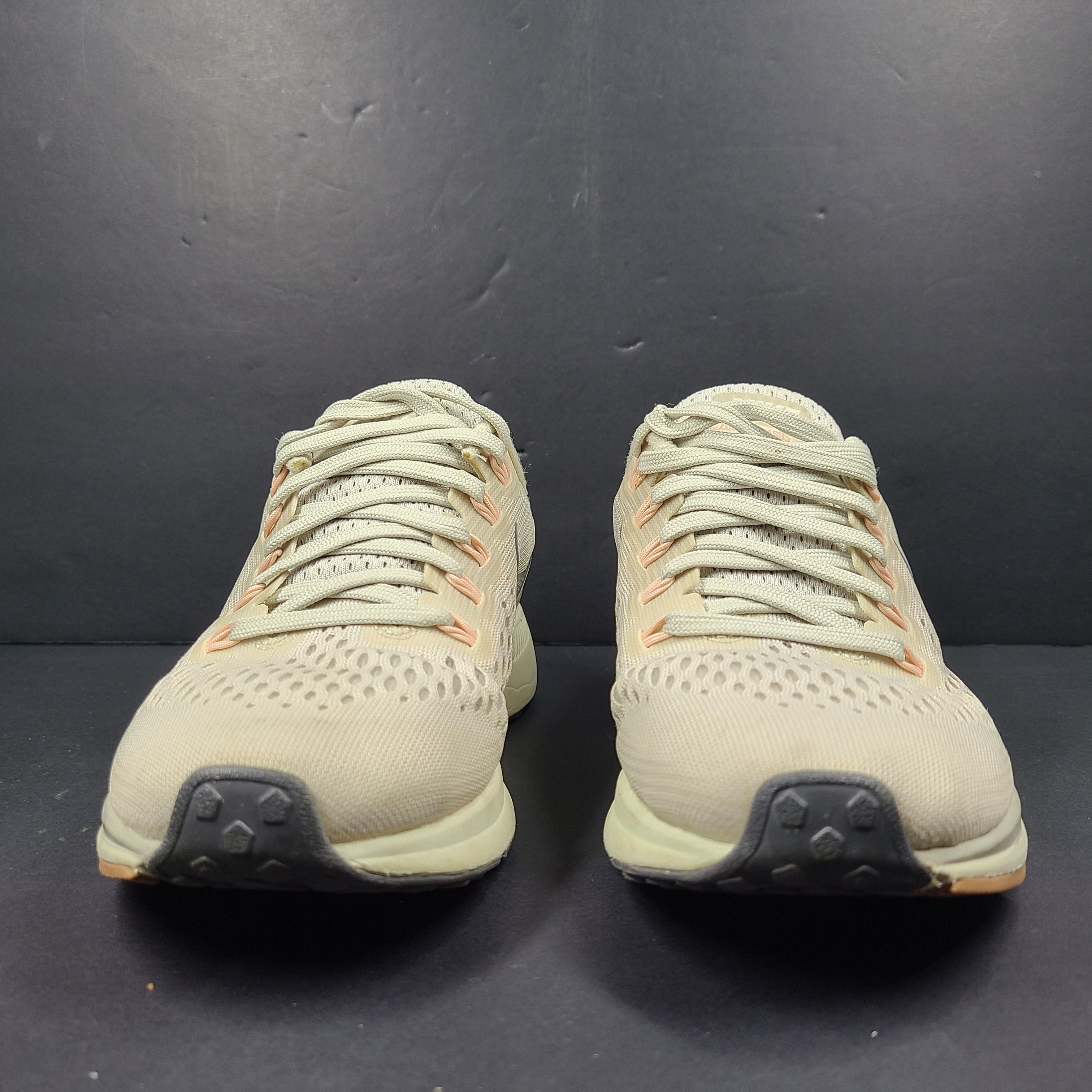 A pair of beige Nike Zoom running shoes.