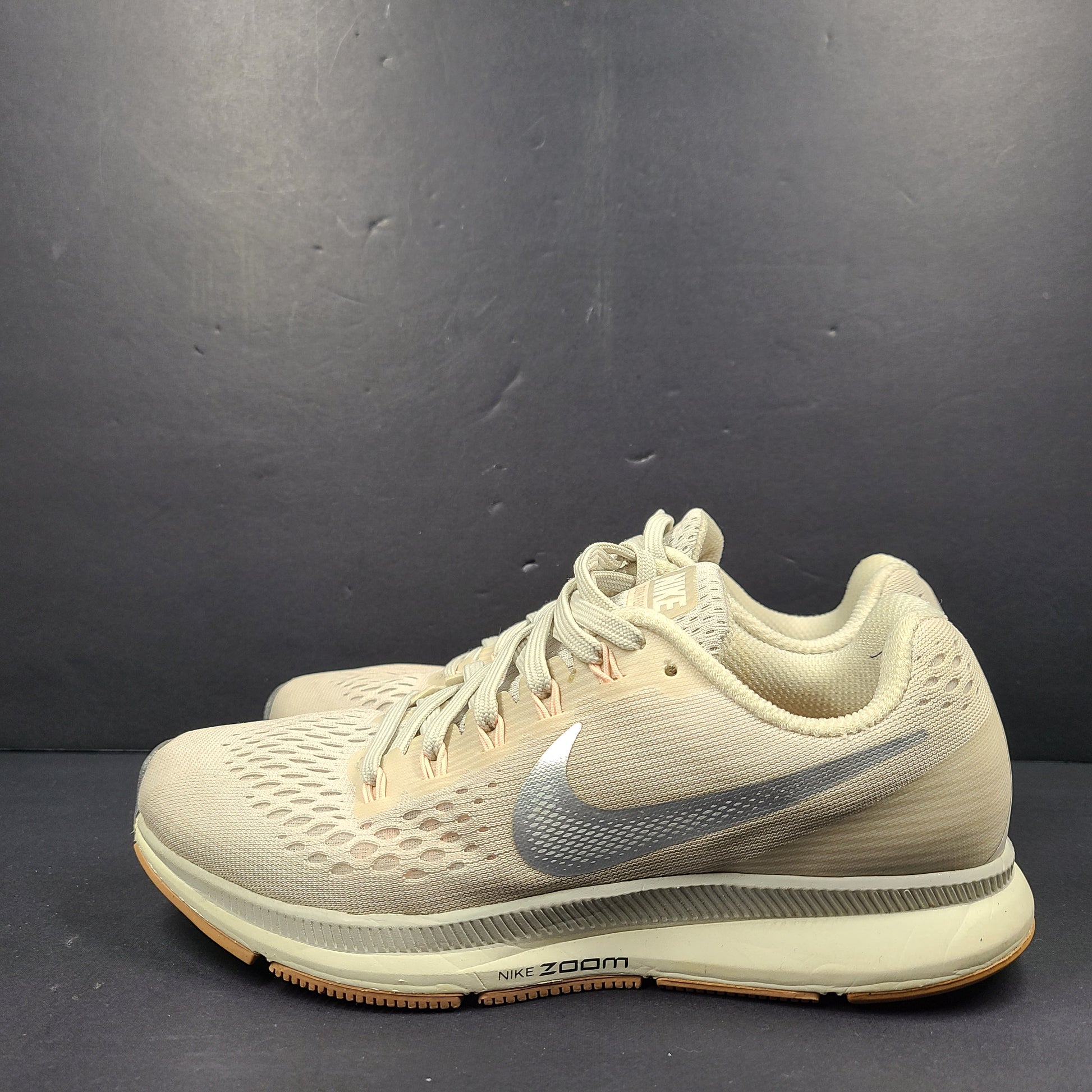 A pair of beige Nike Zoom running shoes.