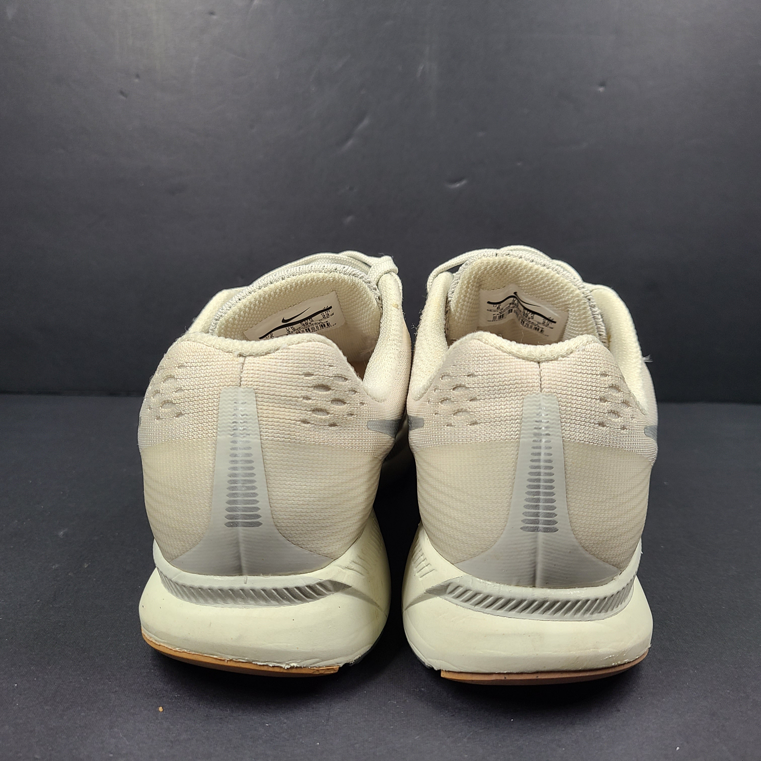 A pair of beige Nike Zoom running shoes.