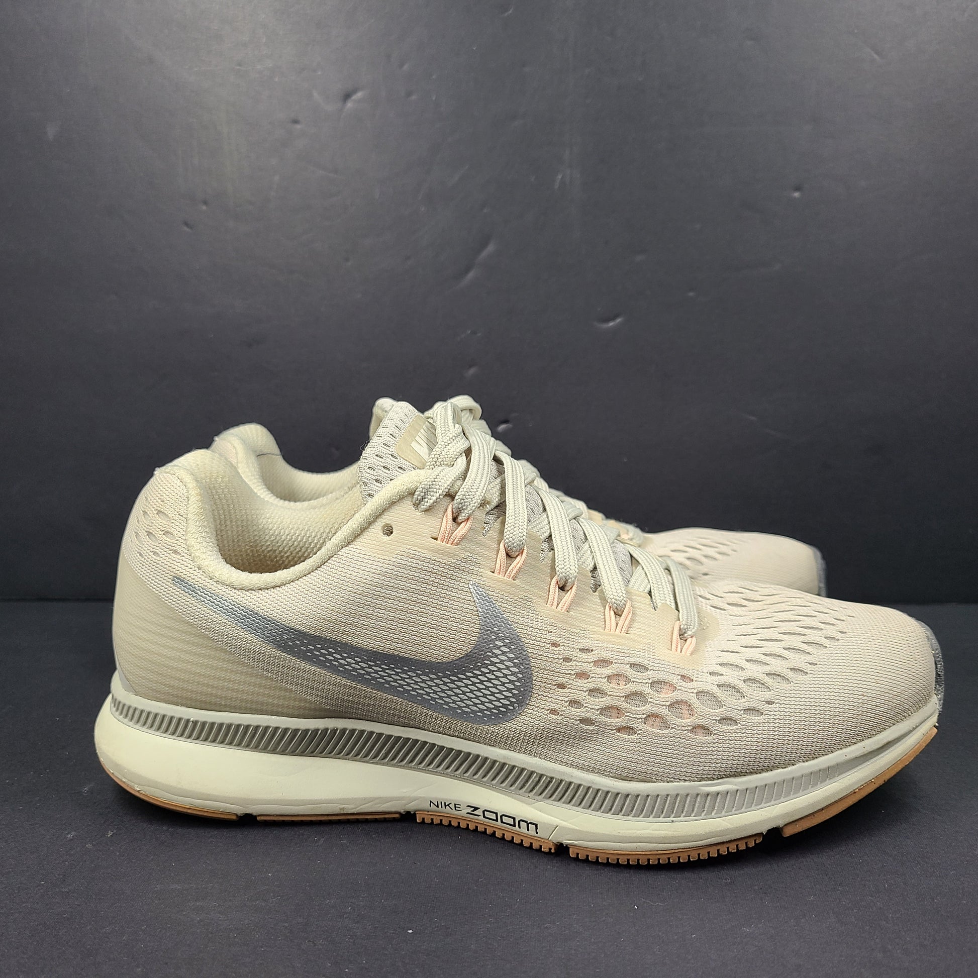 A pair of beige Nike Zoom running shoes.