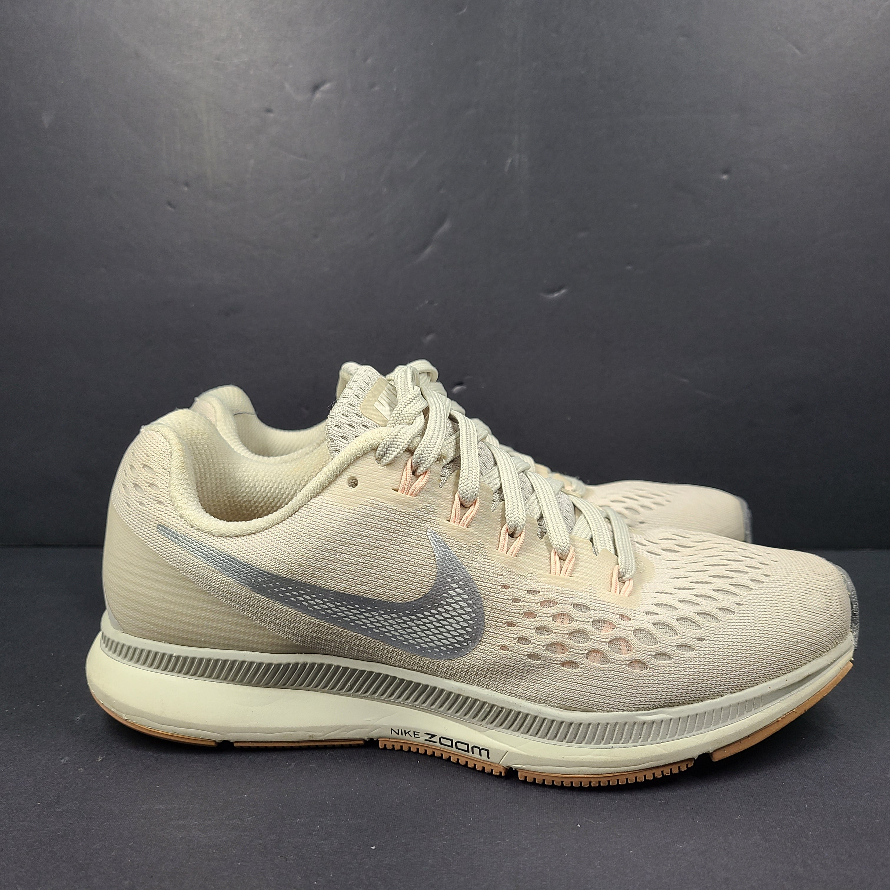 A pair of beige Nike Zoom running shoes.
