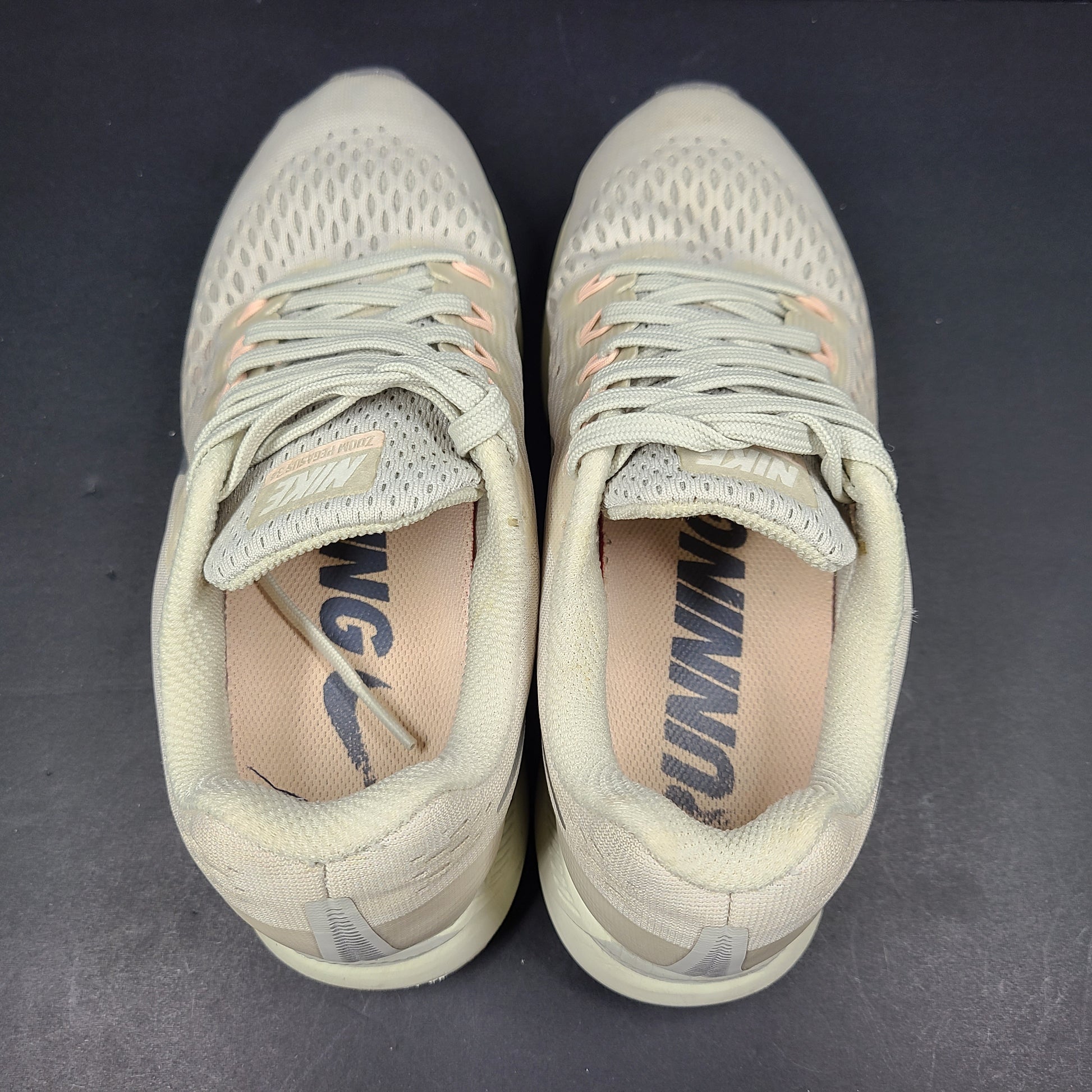 A pair of beige Nike Zoom running shoes.