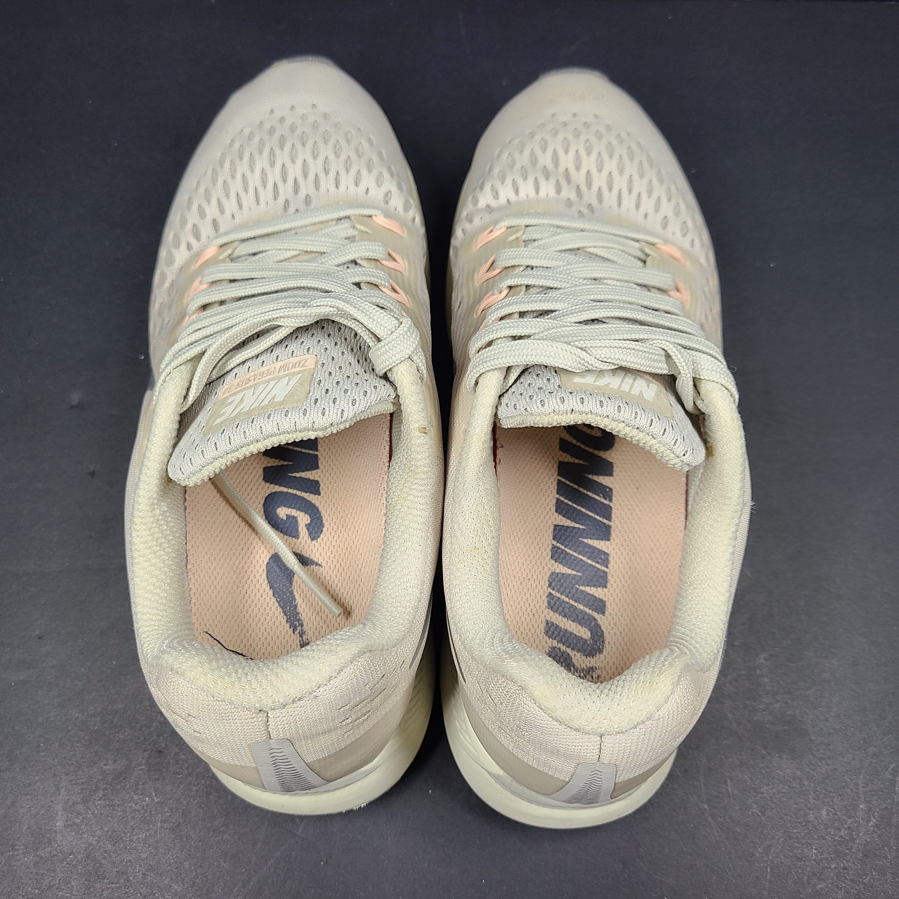 A pair of beige Nike Zoom running shoes.