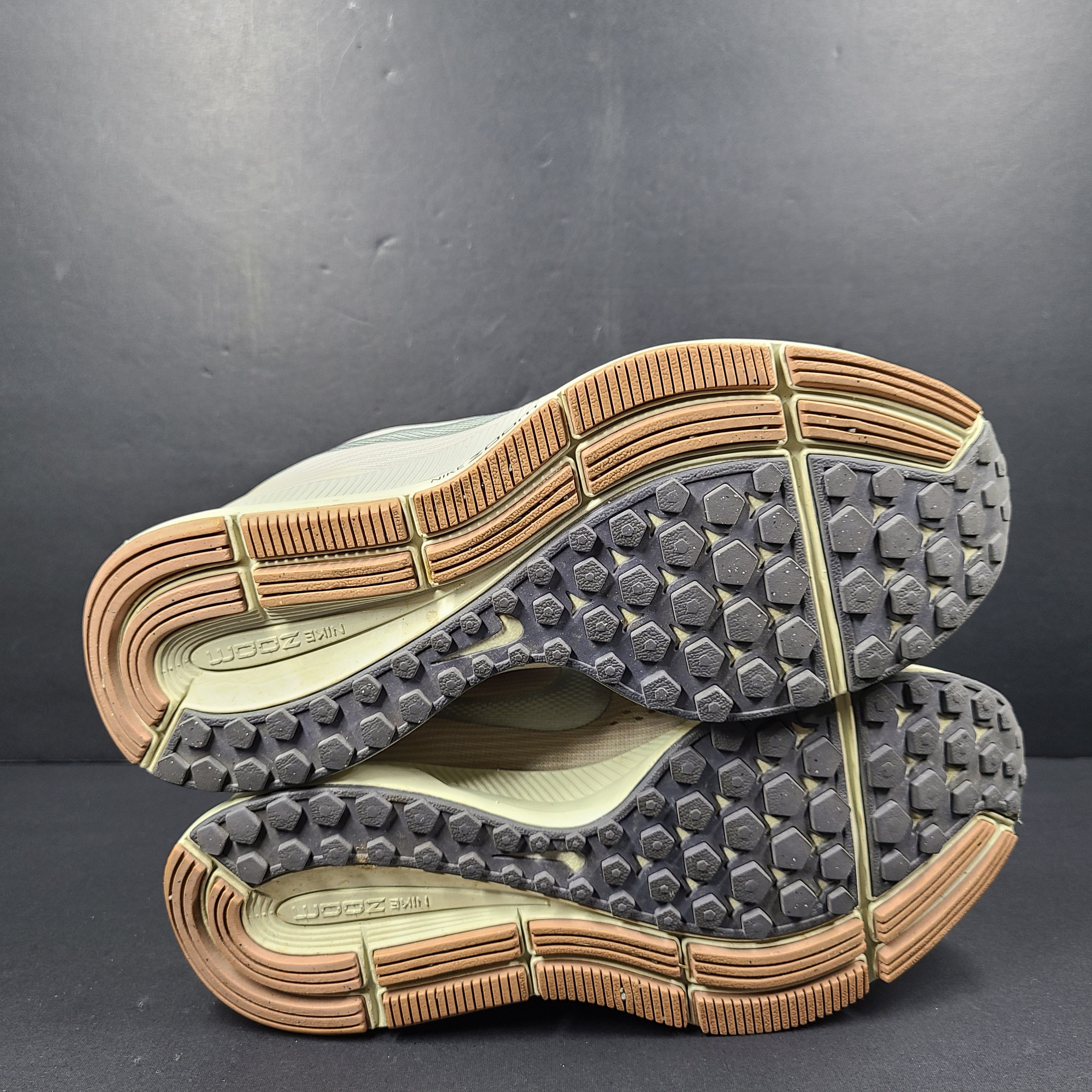A pair of beige Nike Zoom running shoes.
