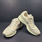 A pair of beige Nike Zoom running shoes.