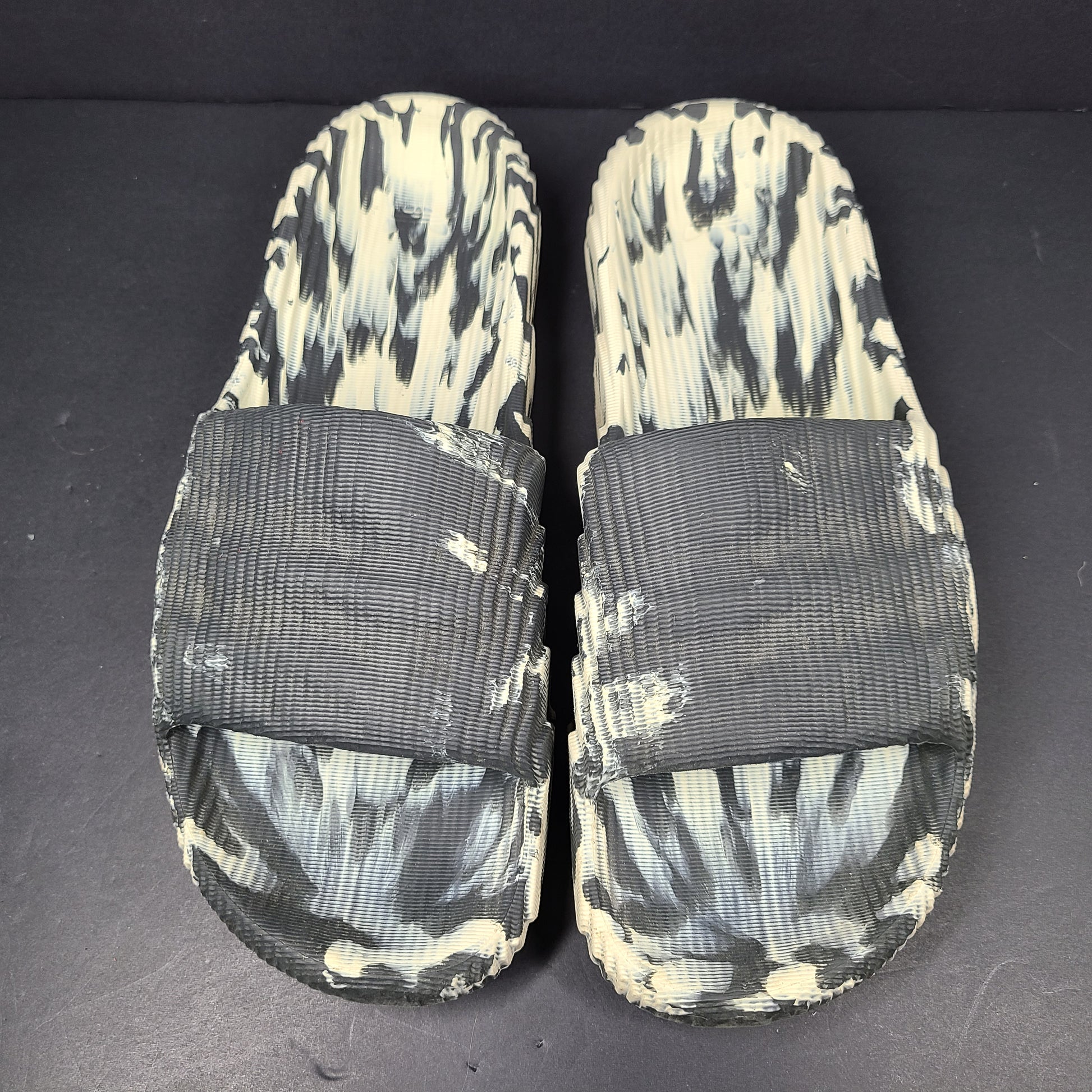 A pair of Adidas Originals Adilette Slides in camo print for men.