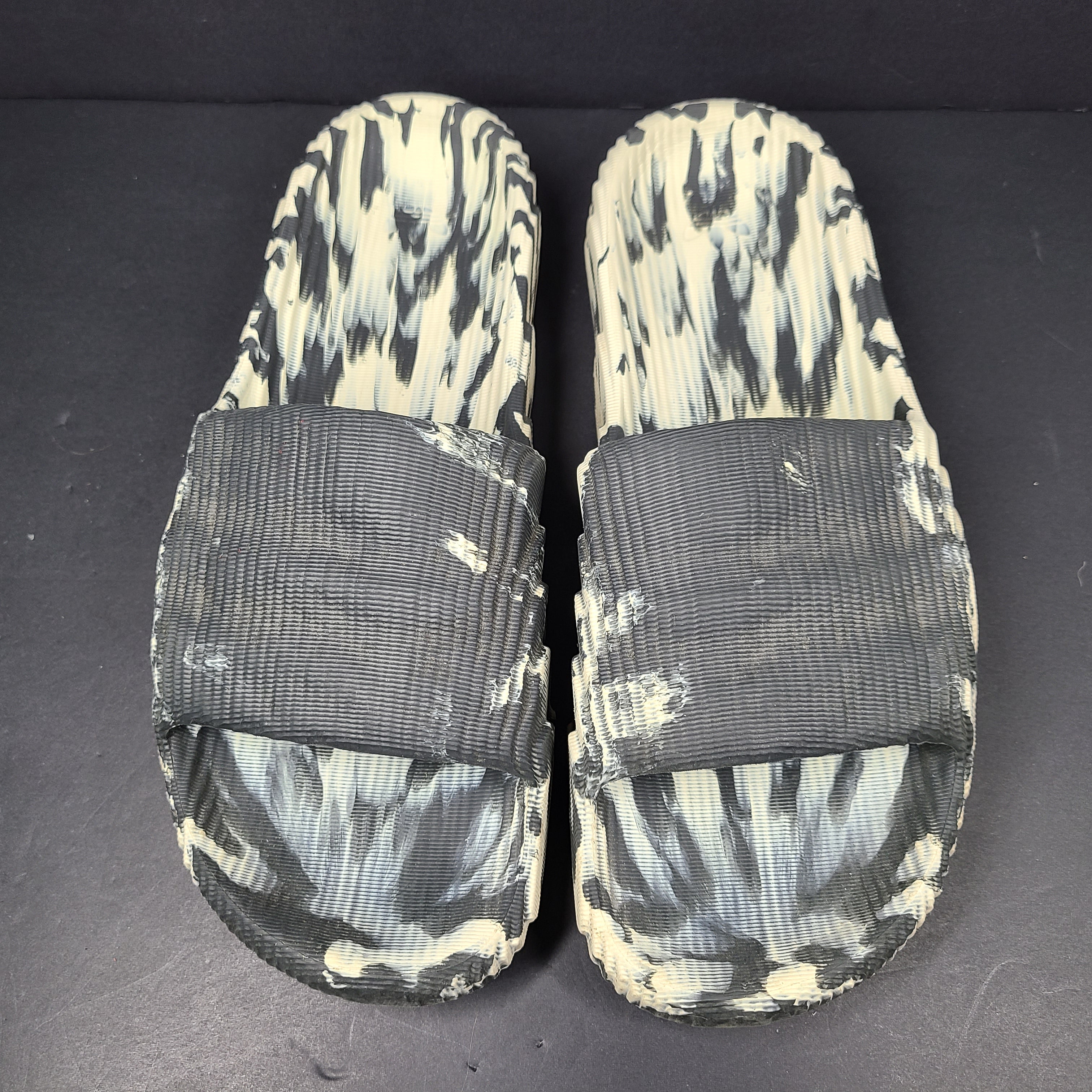 A pair of Adidas Originals Adilette Slides in camo print for men.
