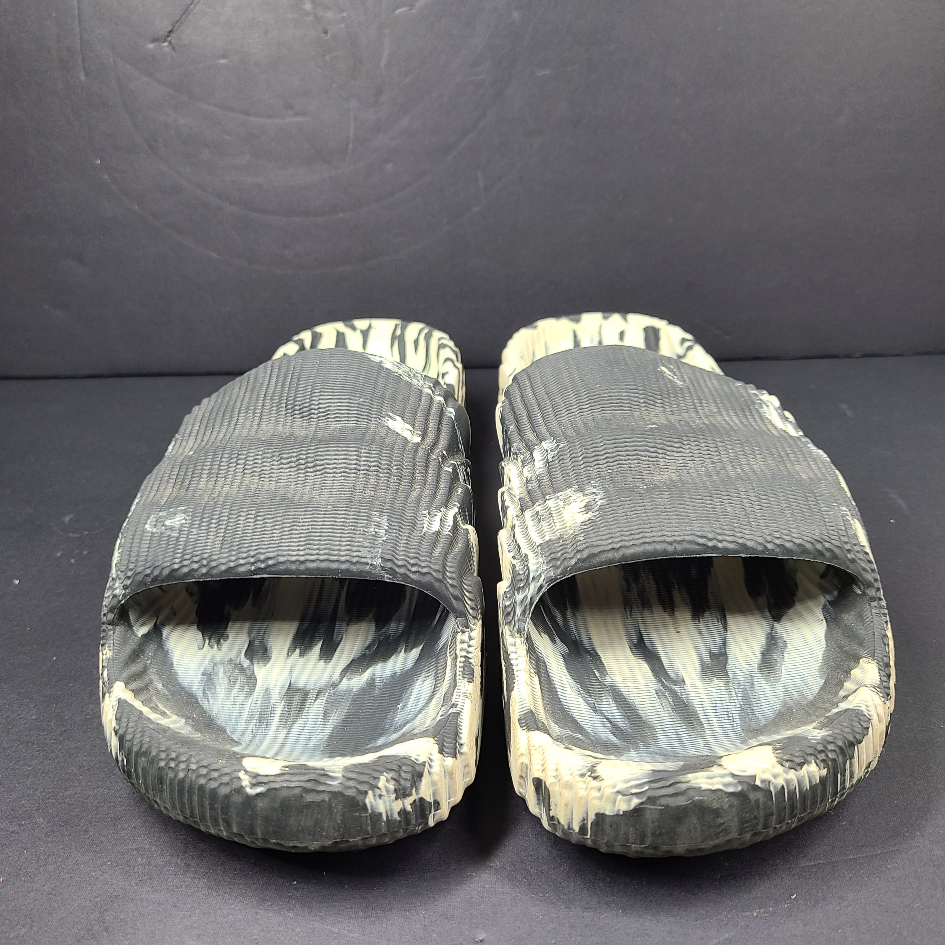 A pair of Adidas Originals Adilette Slides in camo print for men.