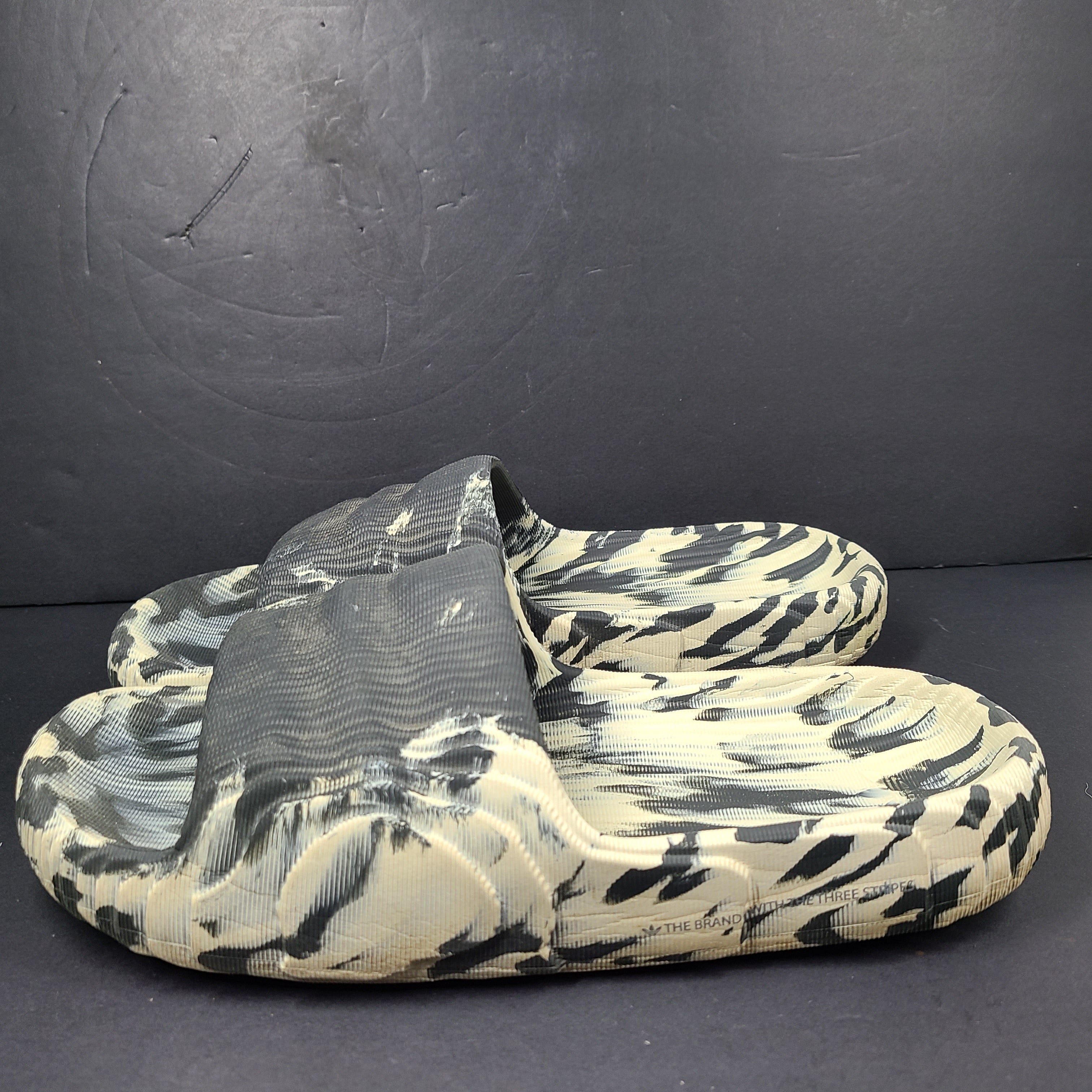 A pair of Adidas Originals Adilette Slides in camo print for men.