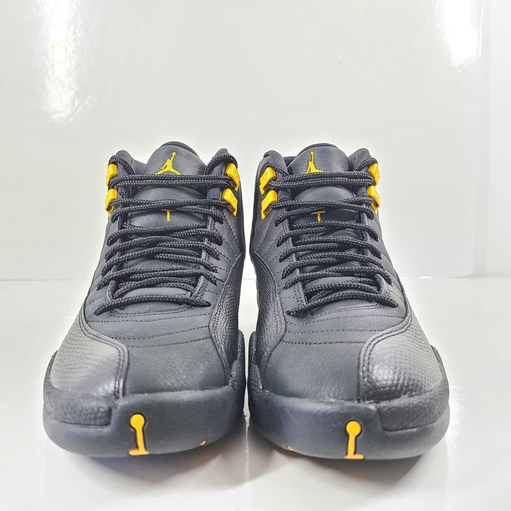 A pair of black and yellow Nike Air Jordan 12 Retro sneakers