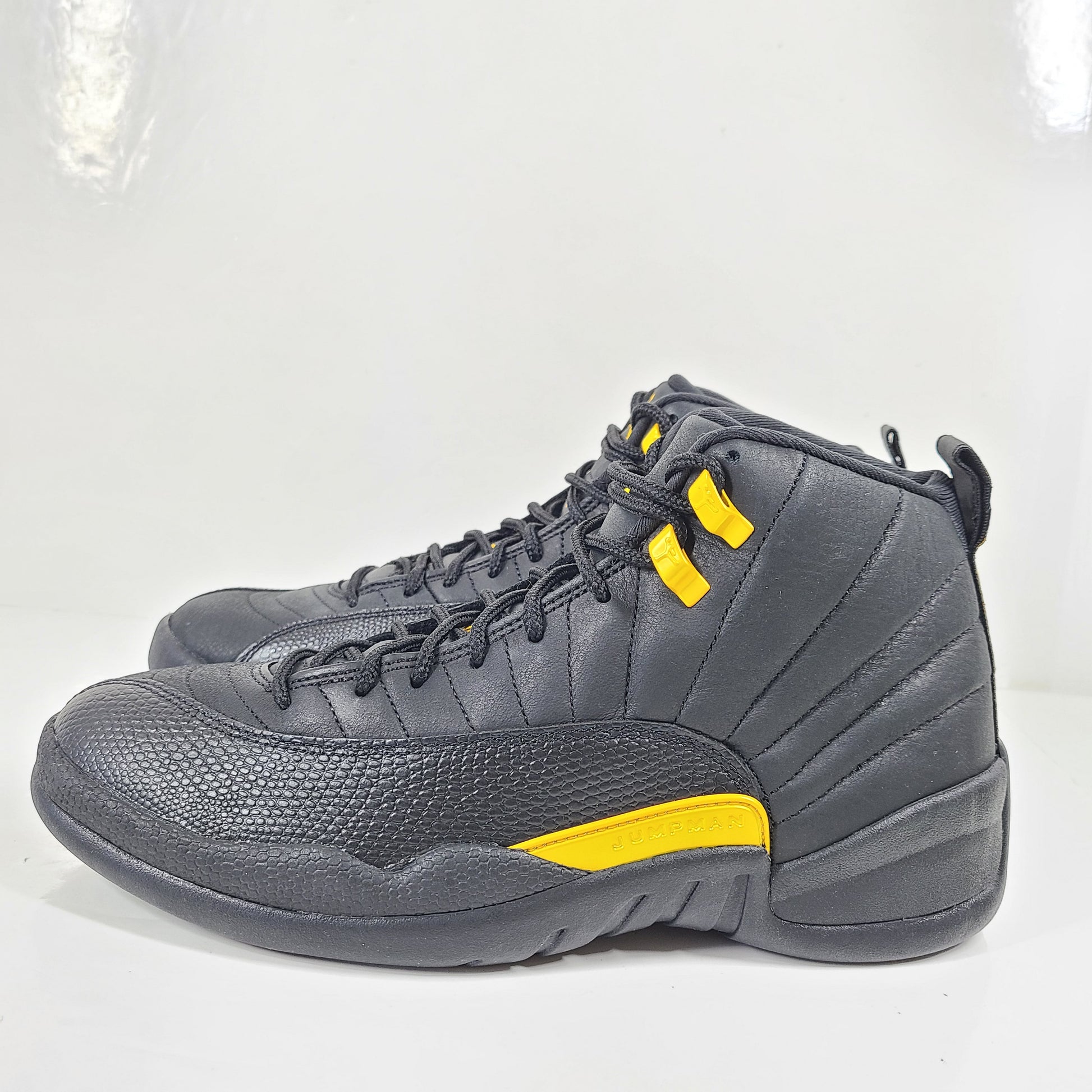 A pair of black and yellow Nike Air Jordan 12 Retro sneakers