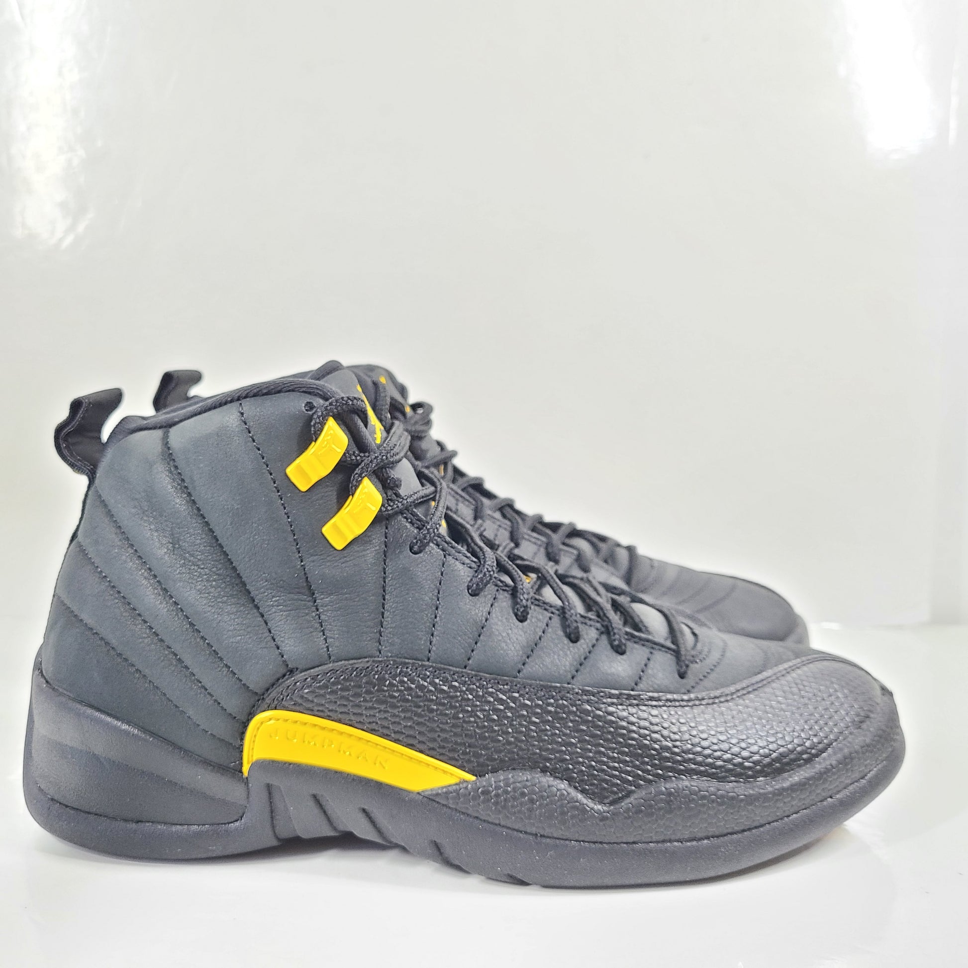 A pair of black and yellow Nike Air Jordan 12 Retro sneakers
