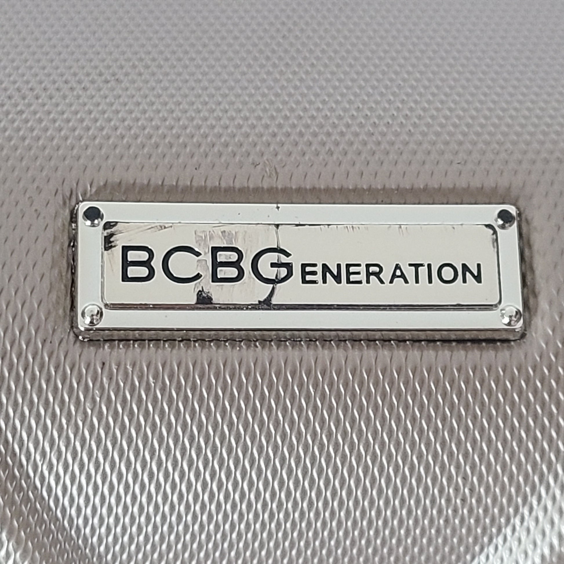 A stylish gold BCBGeneration suitcase made of 100% ABS material.