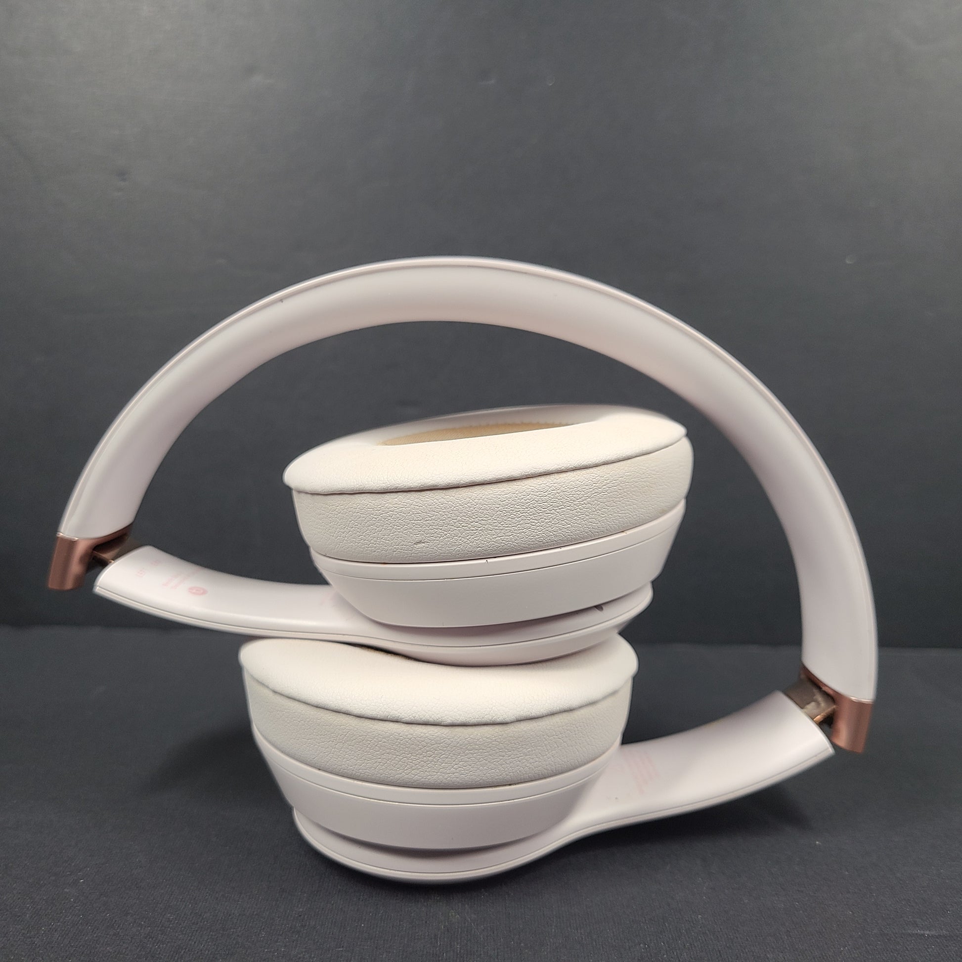 A pair of stylish on-ear headphones in white and rose gold