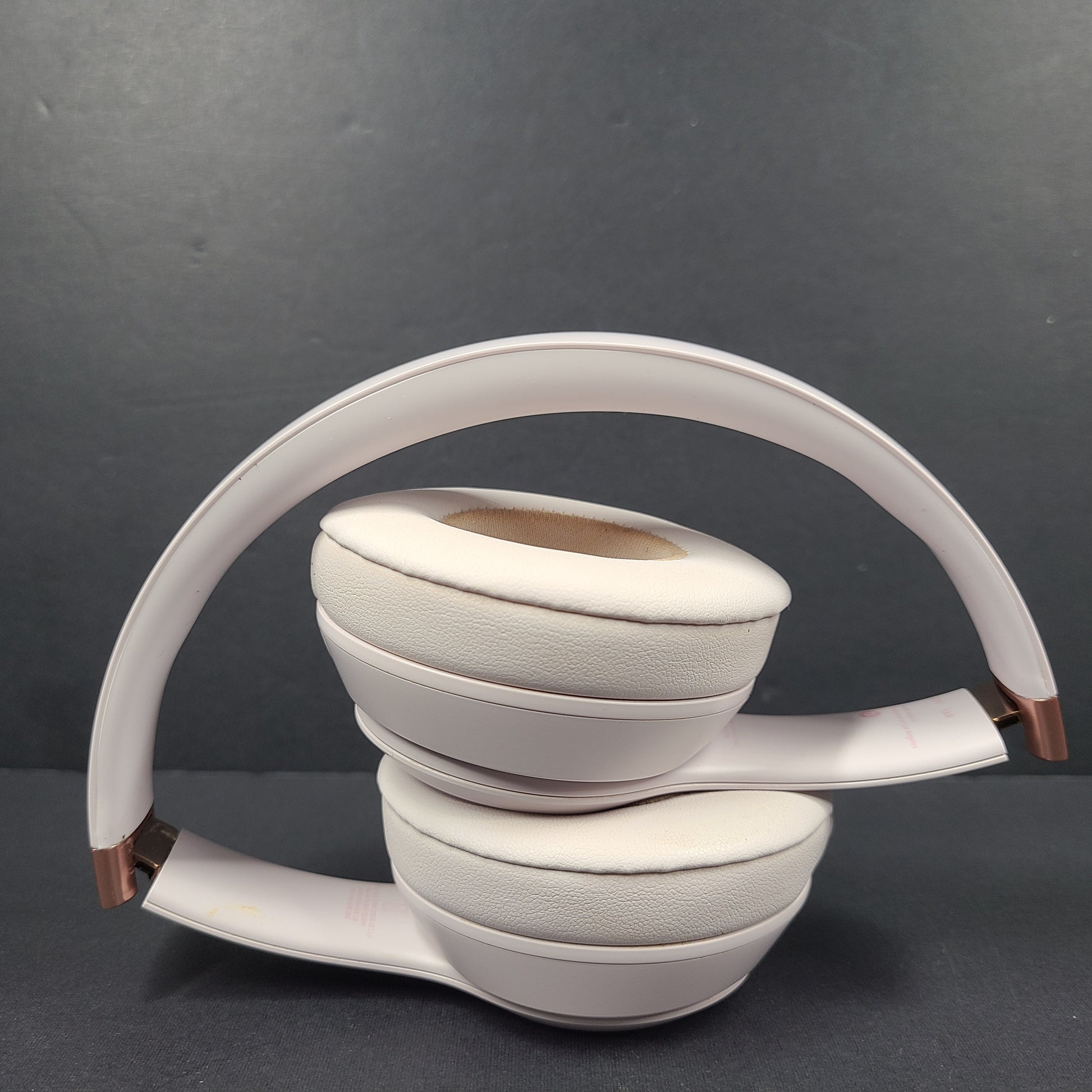 A pair of stylish on-ear headphones in white and rose gold