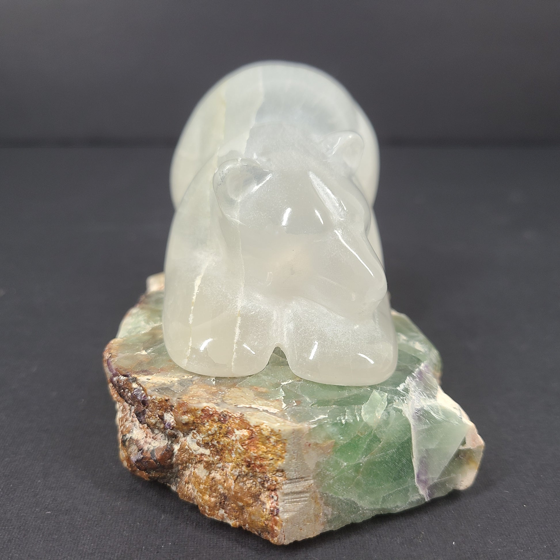 A beautifully hand-carved crystal bear sculpture resting on a stone base.