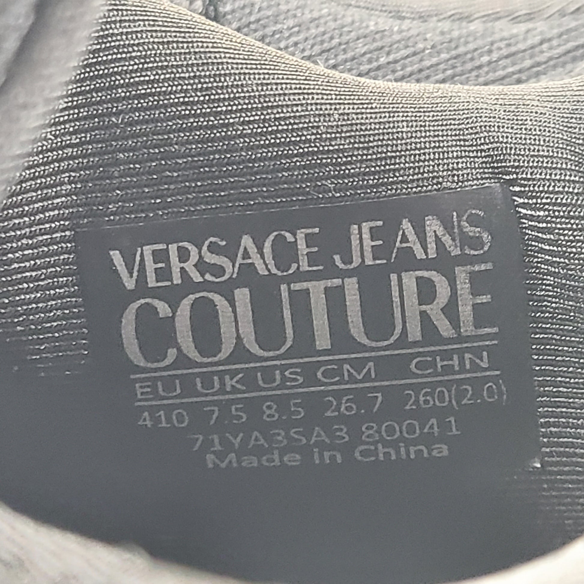 A pair of Versace Jeans Couture black sneakers with slight wear.
