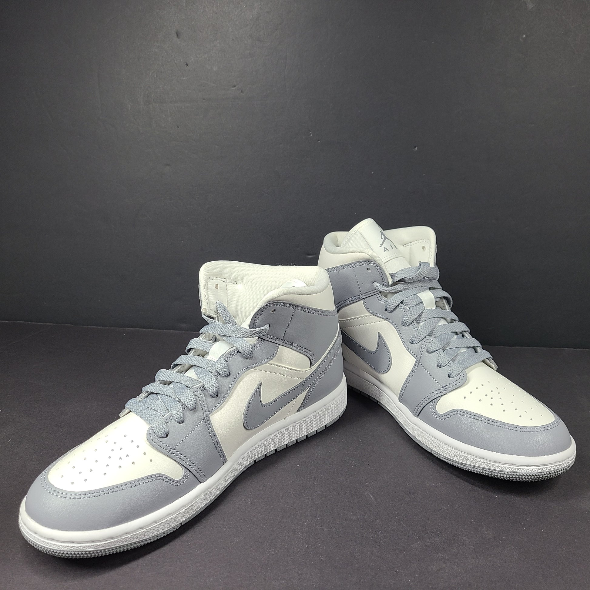 Nike Air Jordan 1 Mid in gray and white with a mid-top profile and classic Swoosh detailing for versatile streetwear styling.