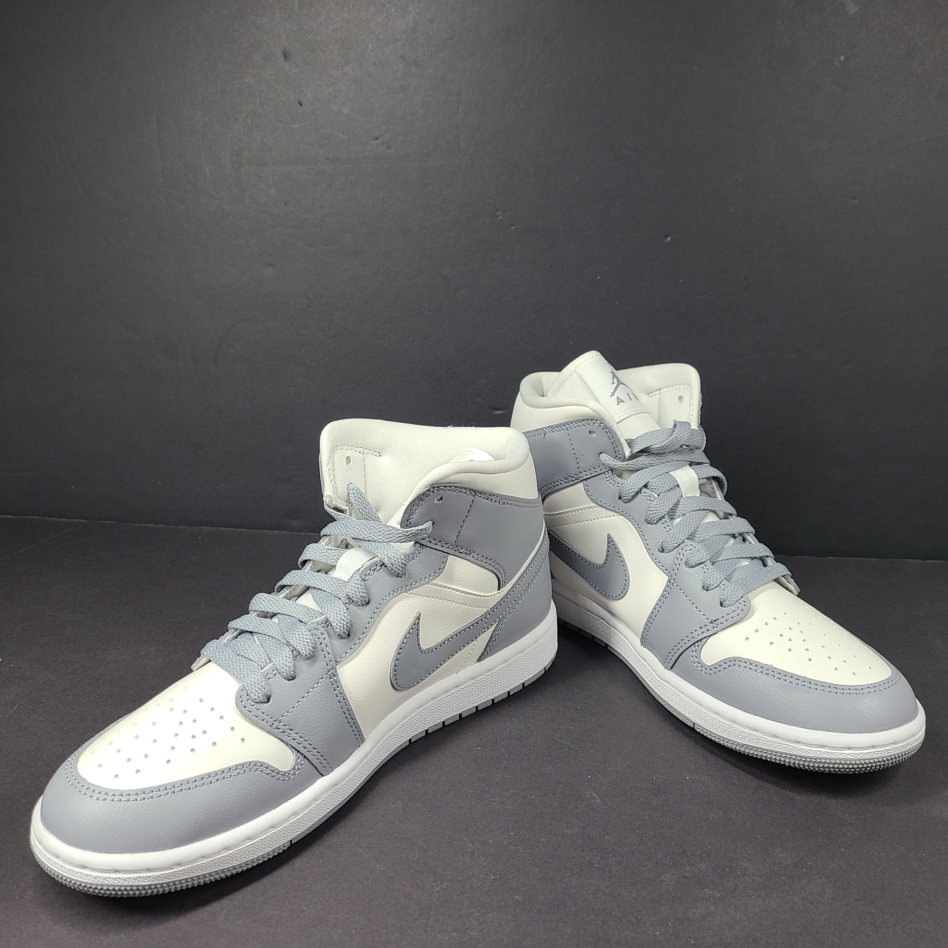 Nike Air Jordan 1 Mid in gray and white with a mid-top profile and classic Swoosh detailing for versatile streetwear styling.
