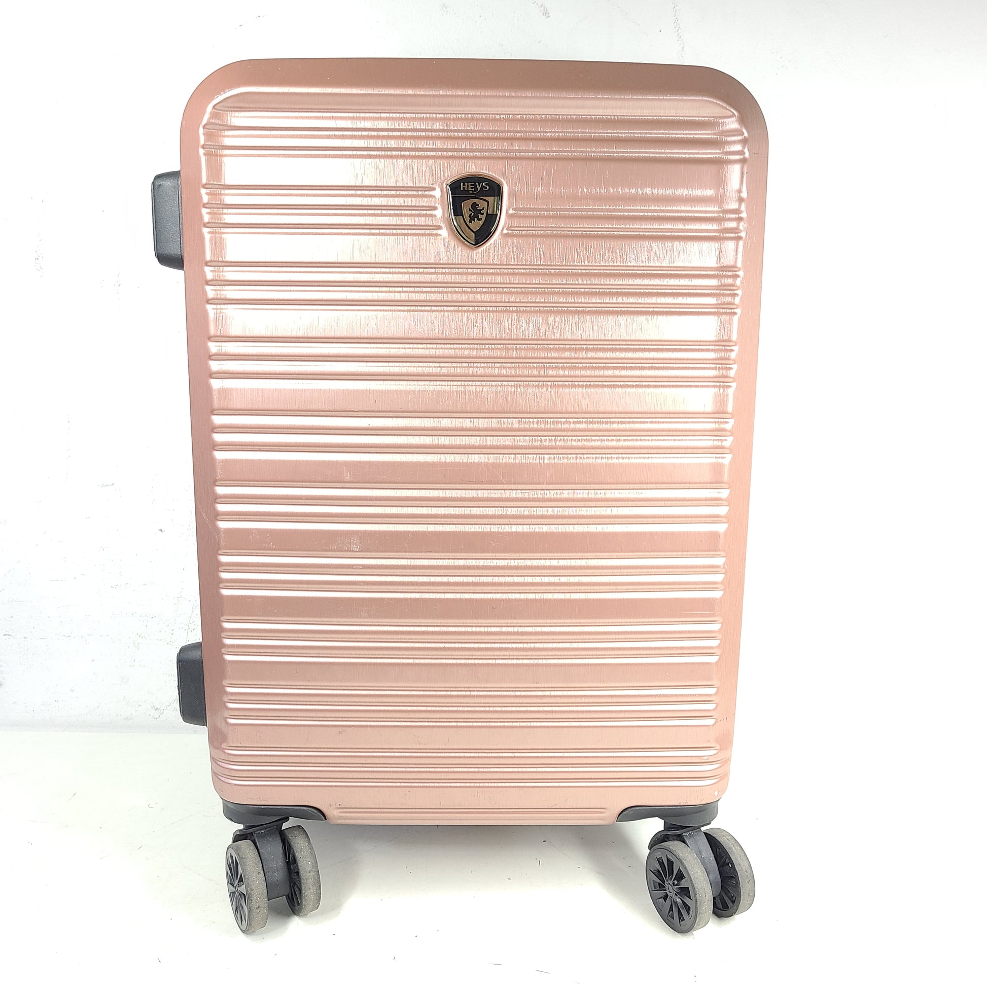 Rose gold Heys Aerolite hardshell carry-on with spinner wheels and telescoping handle for smooth travel.