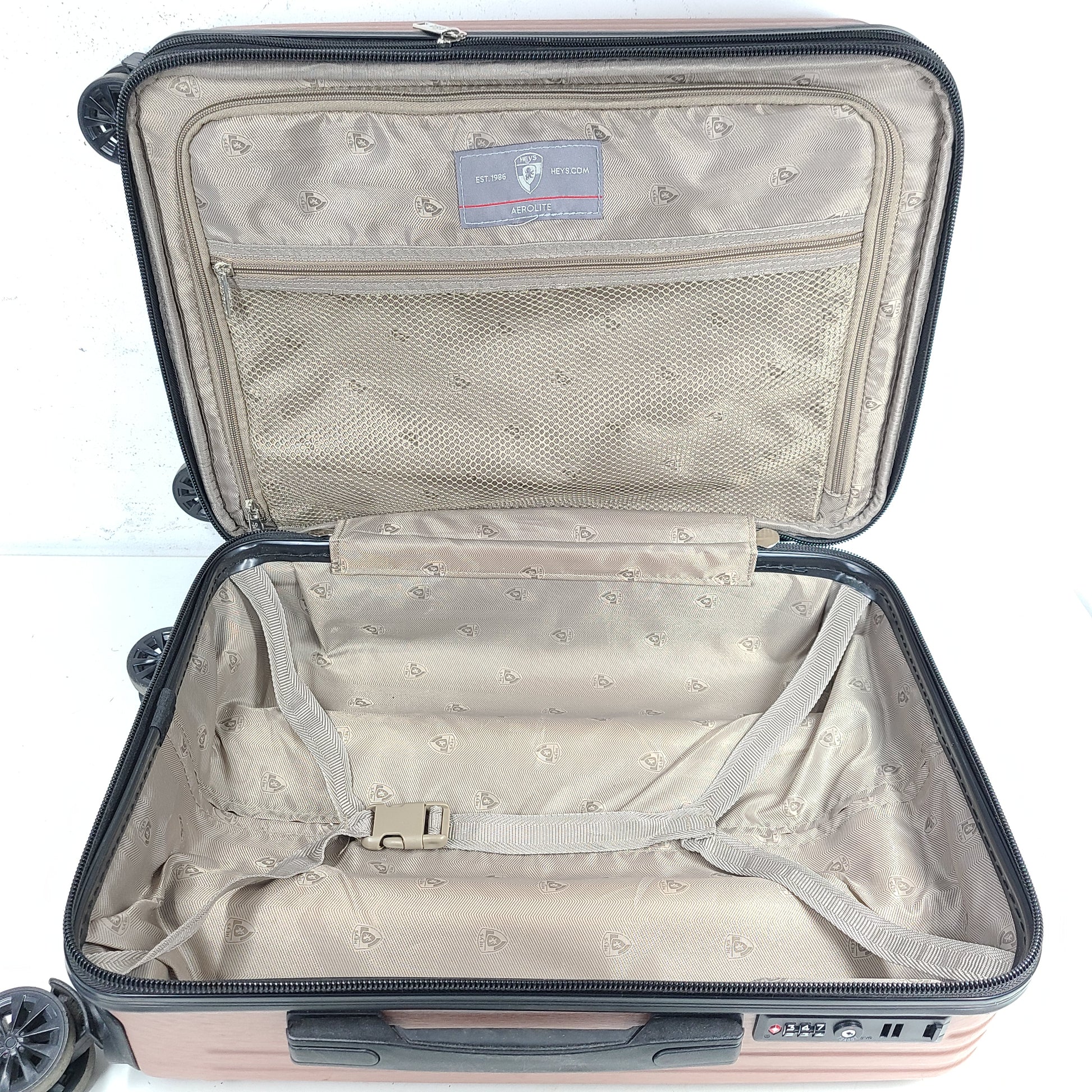 Rose gold Heys Aerolite hardshell carry-on with spinner wheels and telescoping handle for smooth travel.