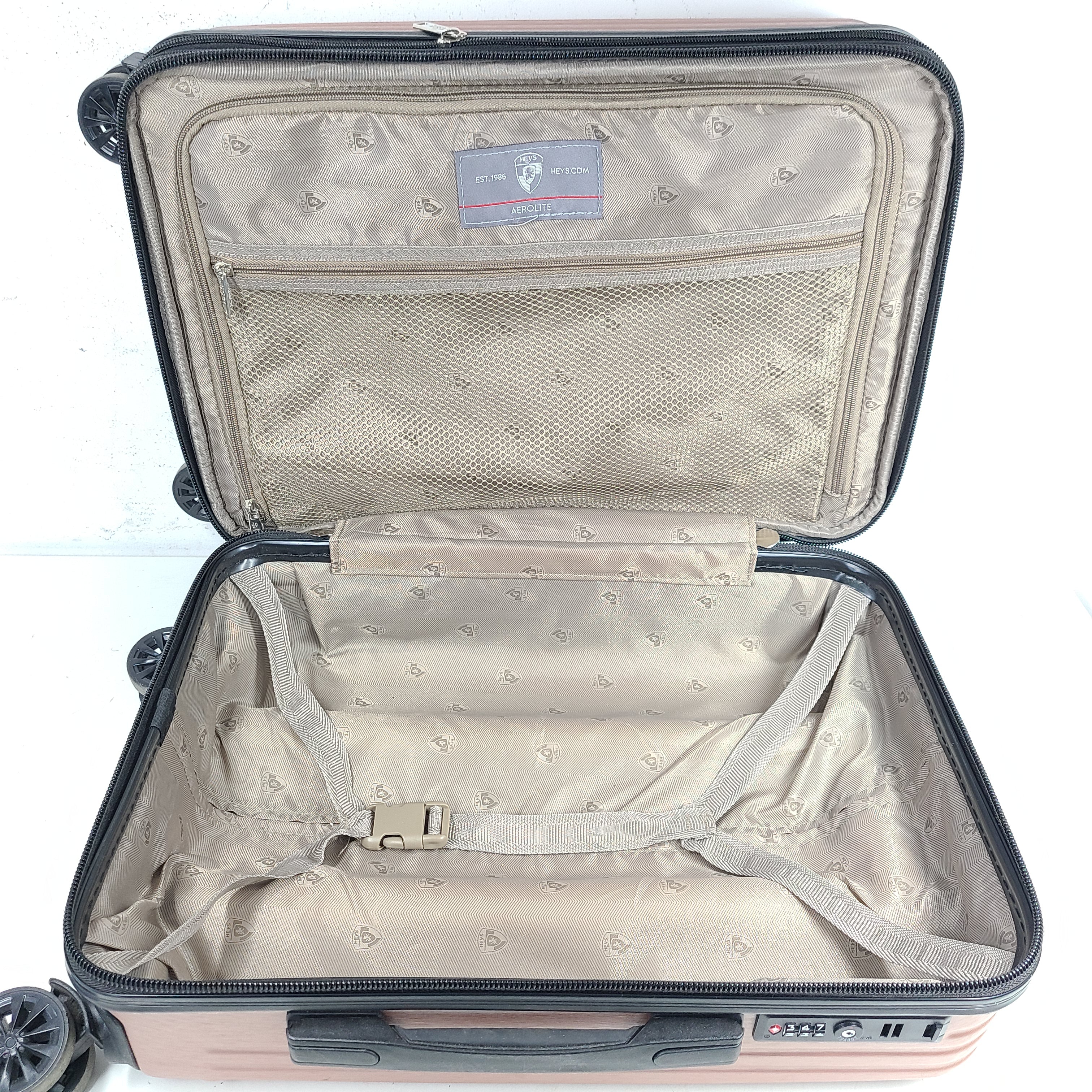 Rose gold Heys Aerolite hardshell carry-on with spinner wheels and telescoping handle for smooth travel.