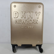 Gold DKNY suitcase with minor surface scratches and a clean interior, branded DKNY NEW YORK EST.1989.
