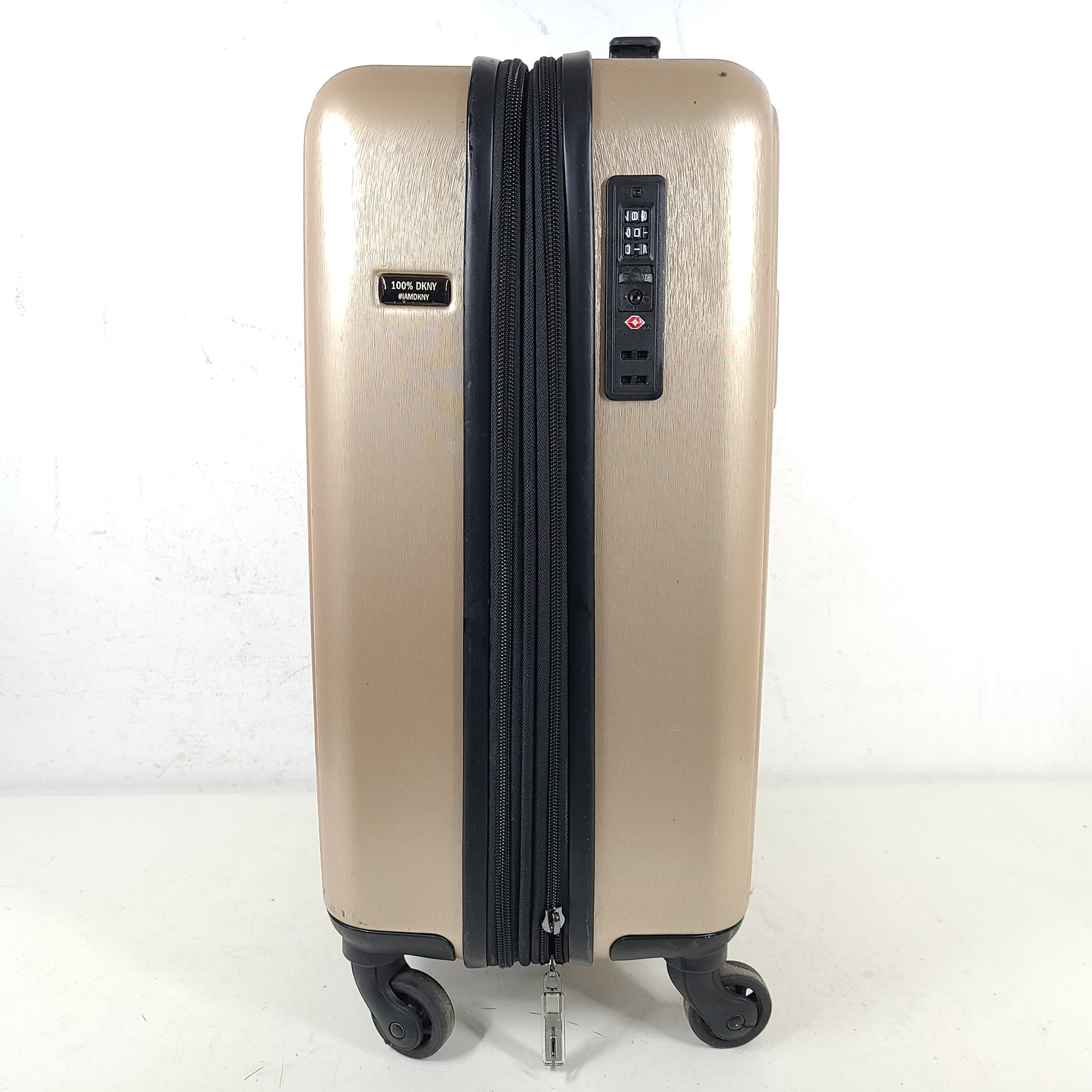 Gold DKNY suitcase with minor surface scratches and a clean interior, branded DKNY NEW YORK EST.1989.