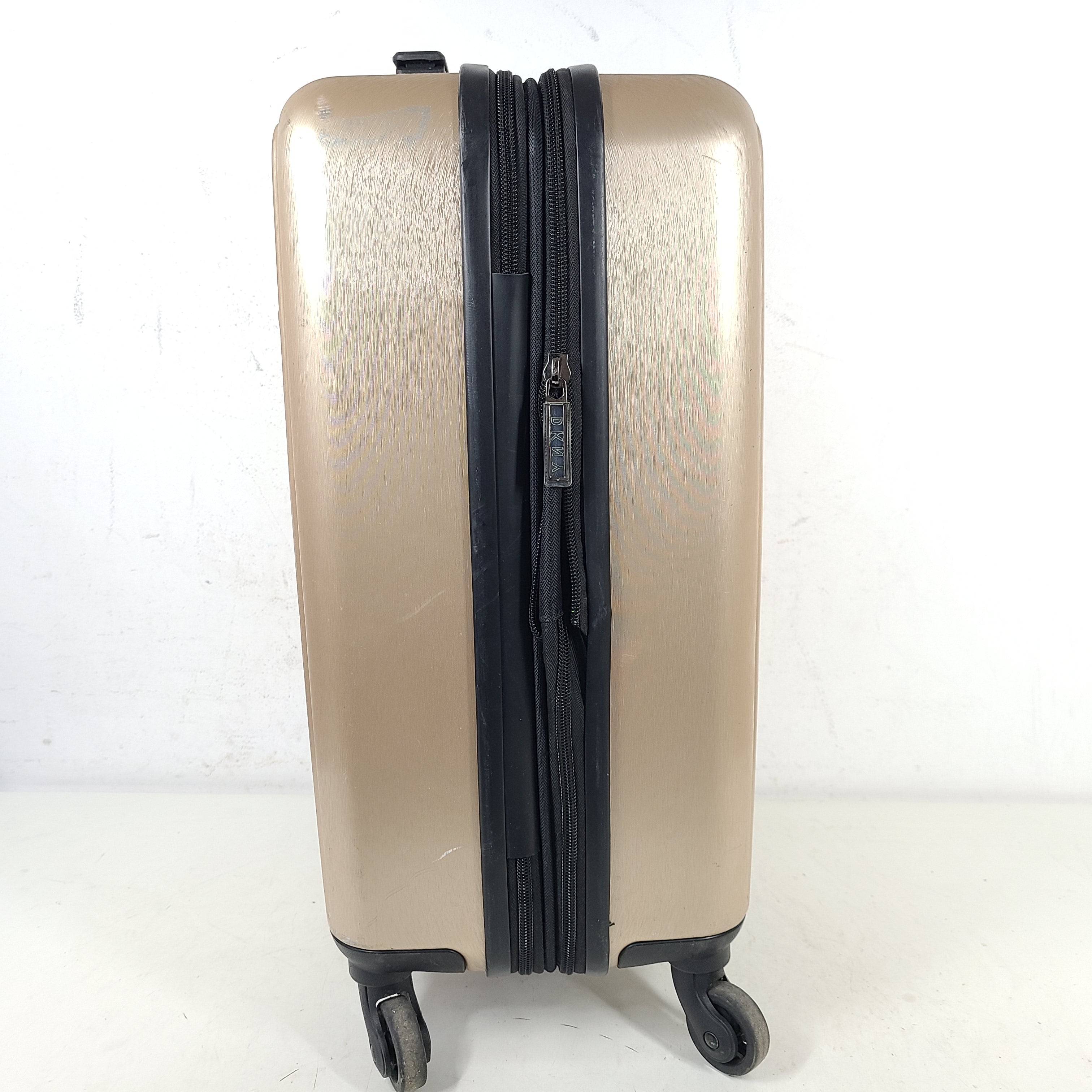 Gold DKNY suitcase with minor surface scratches and a clean interior, branded DKNY NEW YORK EST.1989.