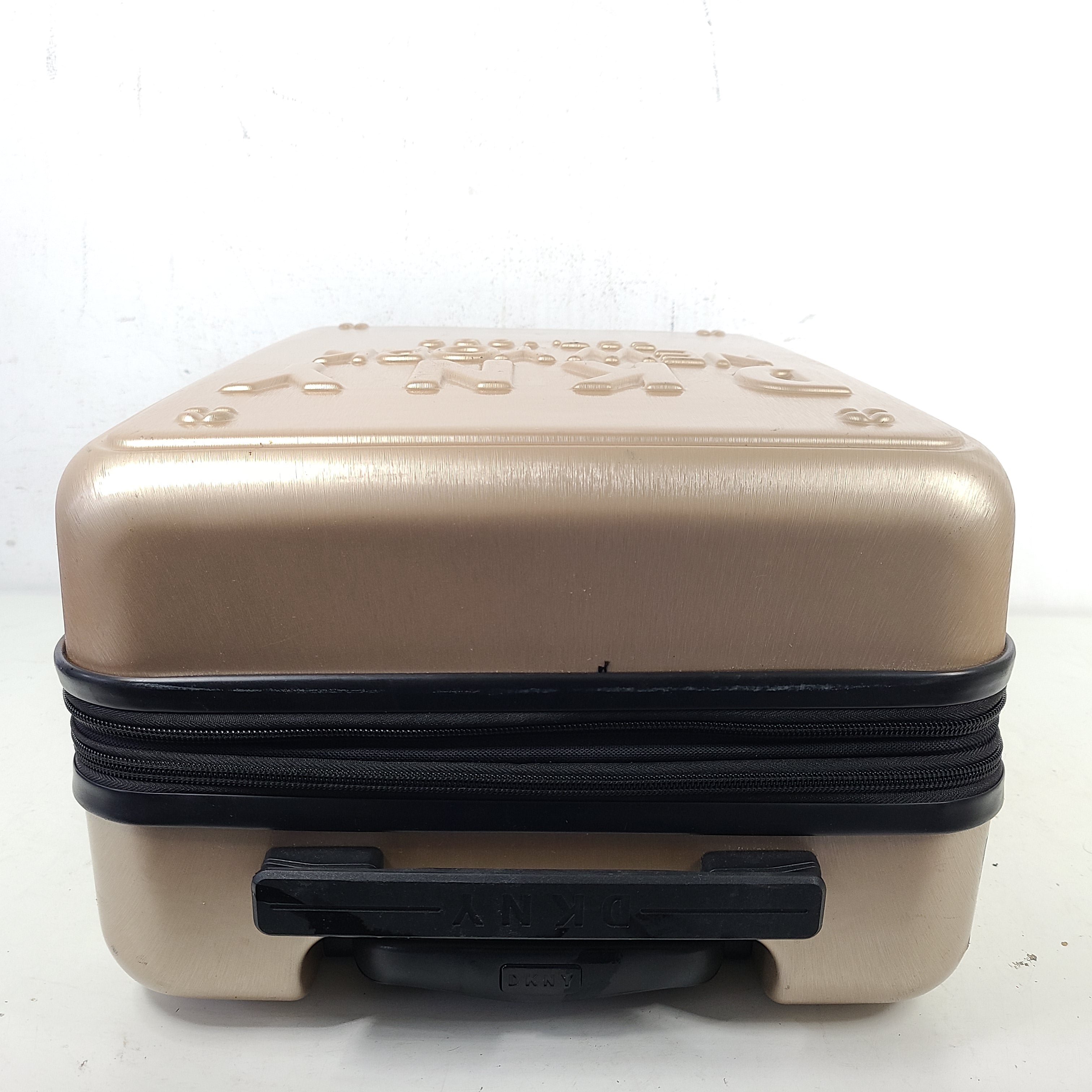 Gold DKNY suitcase with minor surface scratches and a clean interior, branded DKNY NEW YORK EST.1989.