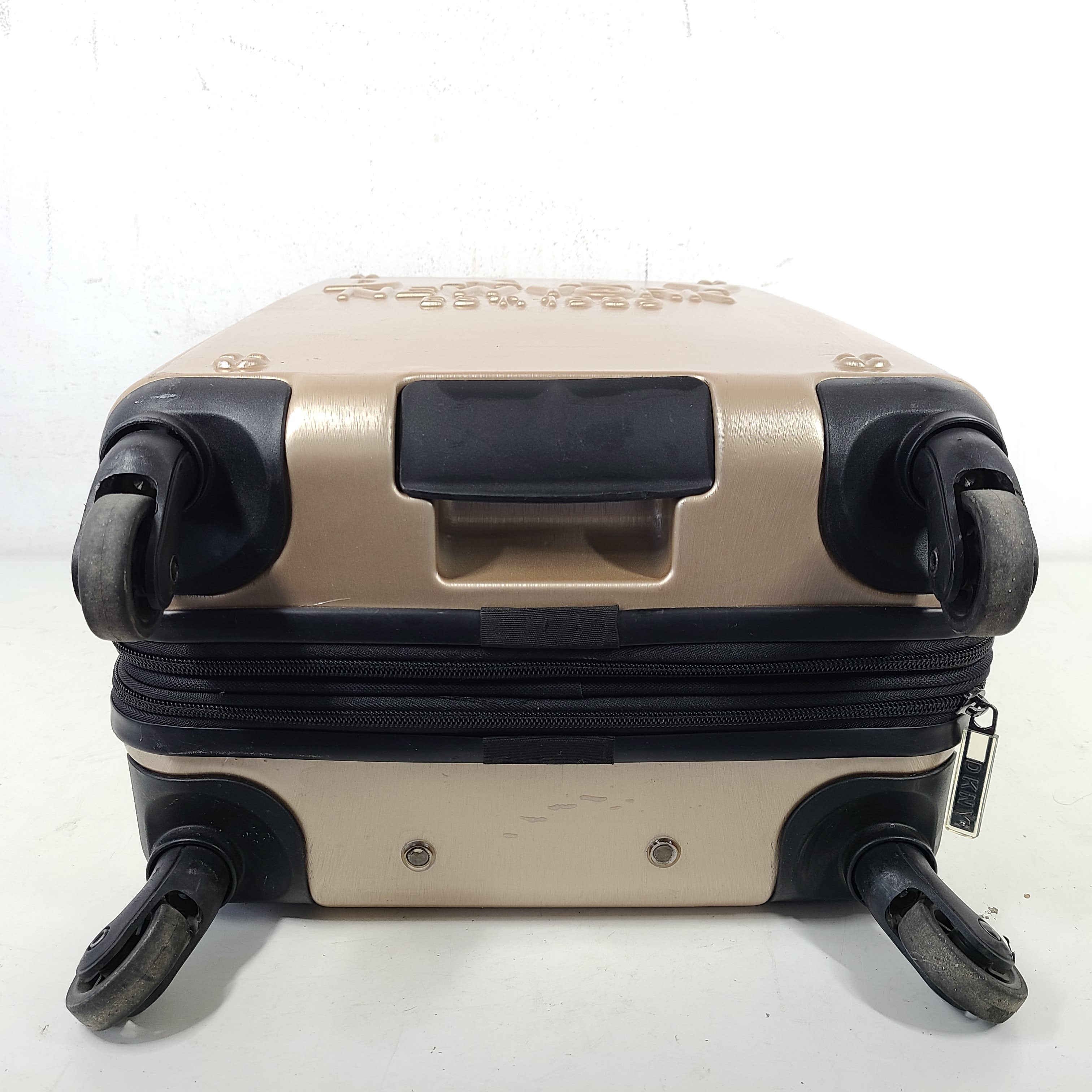 Gold DKNY suitcase with minor surface scratches and a clean interior, branded DKNY NEW YORK EST.1989.