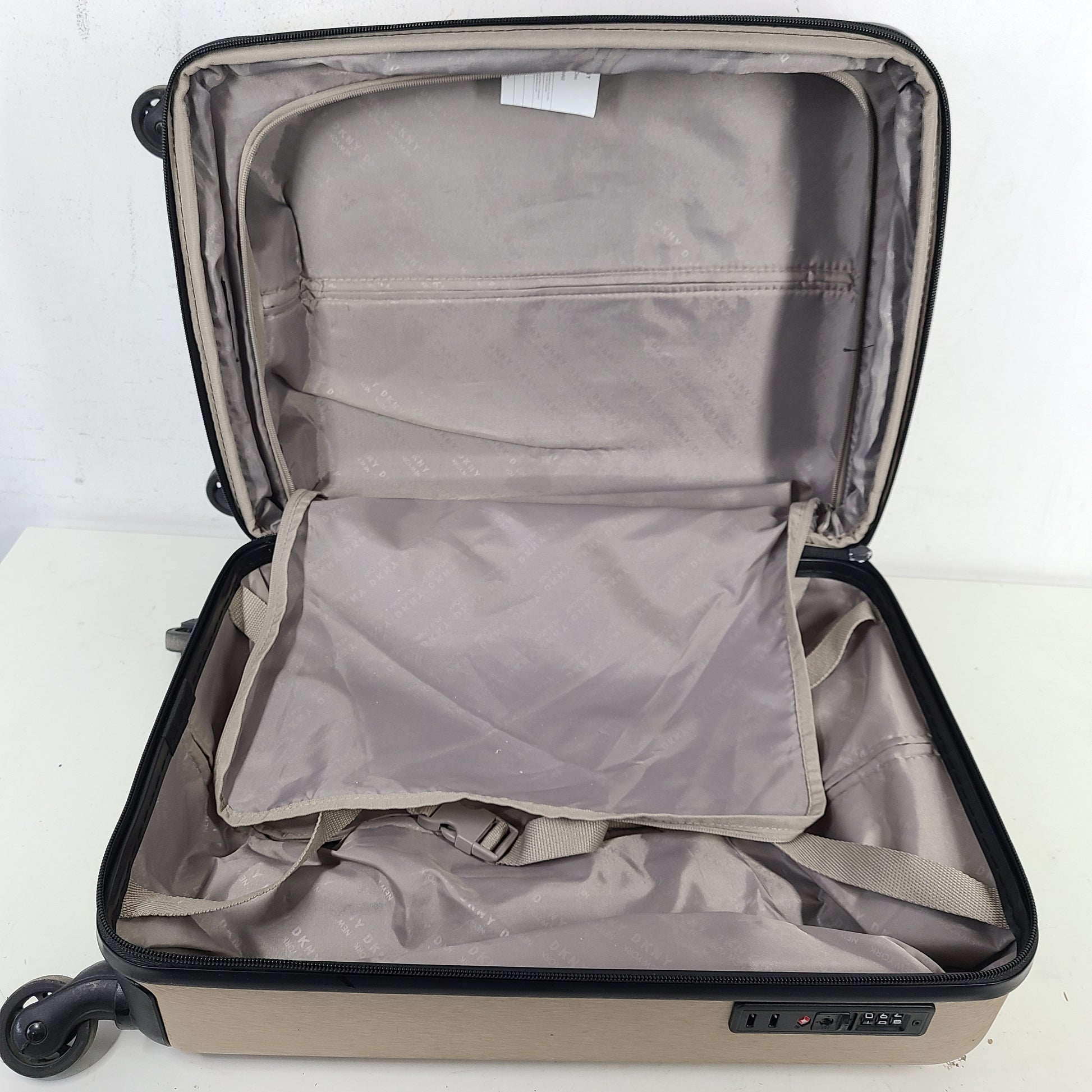 Gold DKNY suitcase with minor surface scratches and a clean interior, branded DKNY NEW YORK EST.1989.