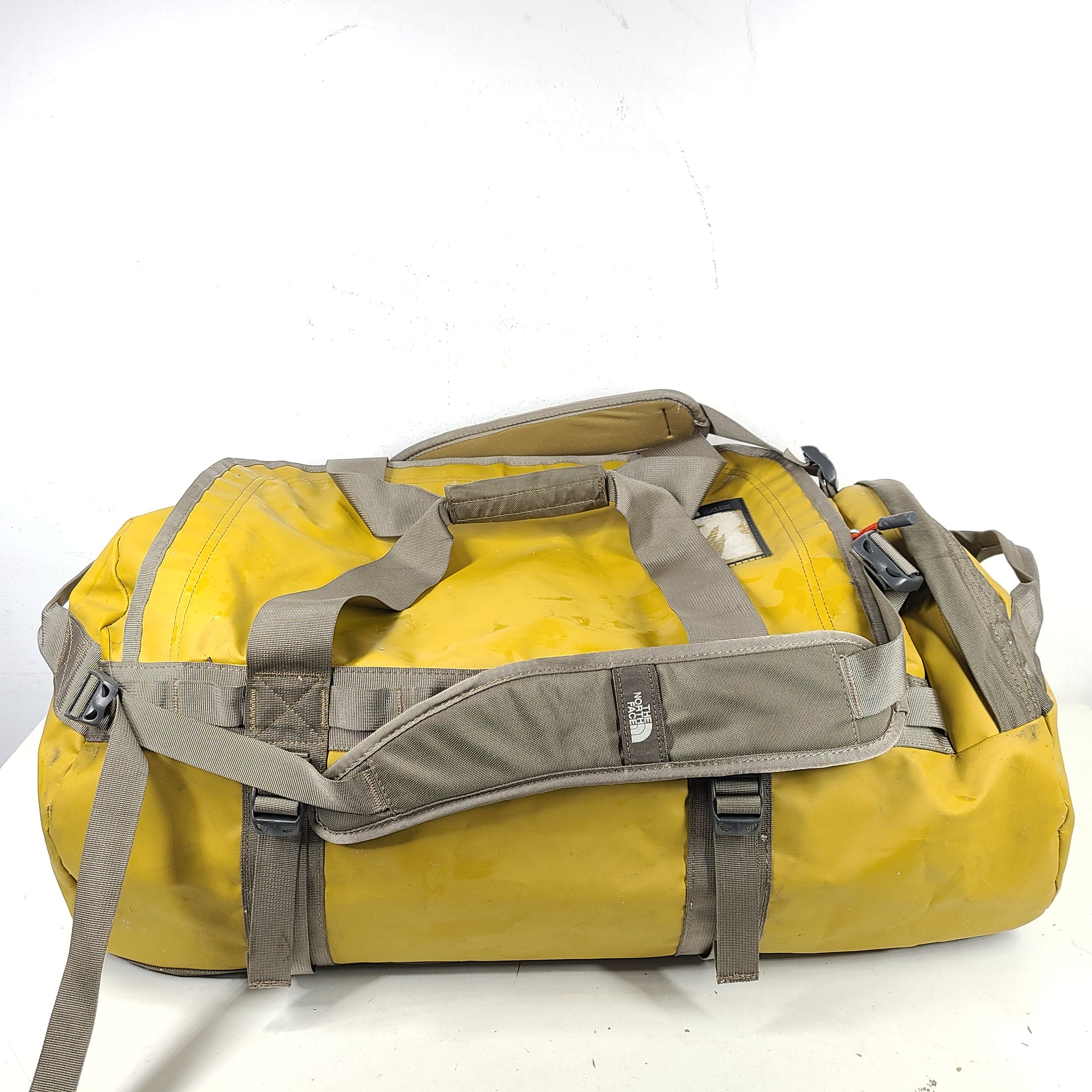 The North Face medium Base Camp duffel in yellow and grey with reinforced handles and adjustable shoulder straps.