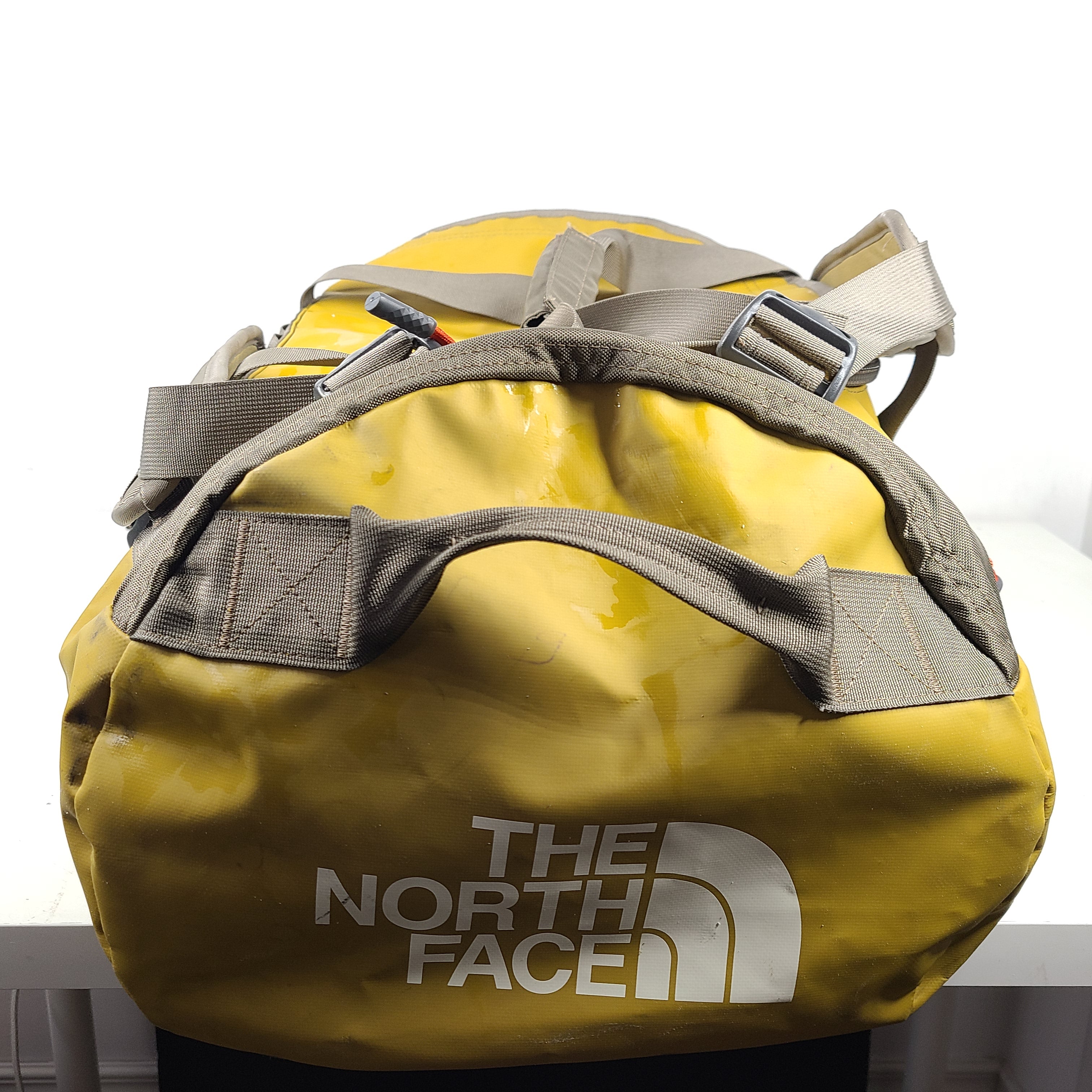 The North Face medium Base Camp duffel in yellow and grey with reinforced handles and adjustable shoulder straps.