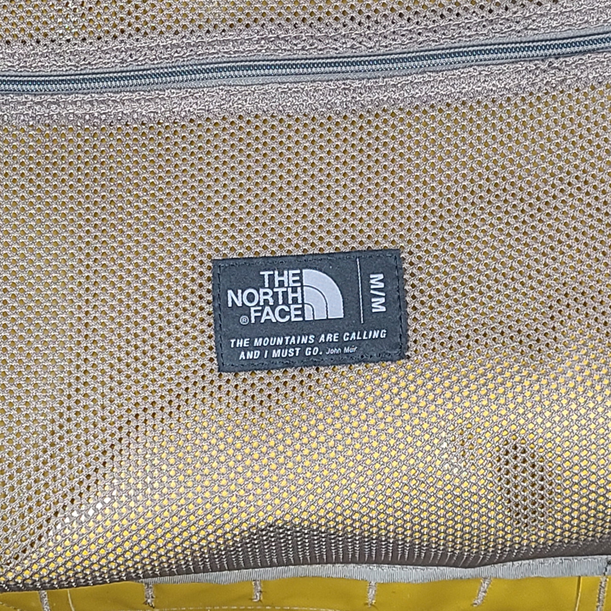 The North Face medium Base Camp duffel in yellow and grey with reinforced handles and adjustable shoulder straps.