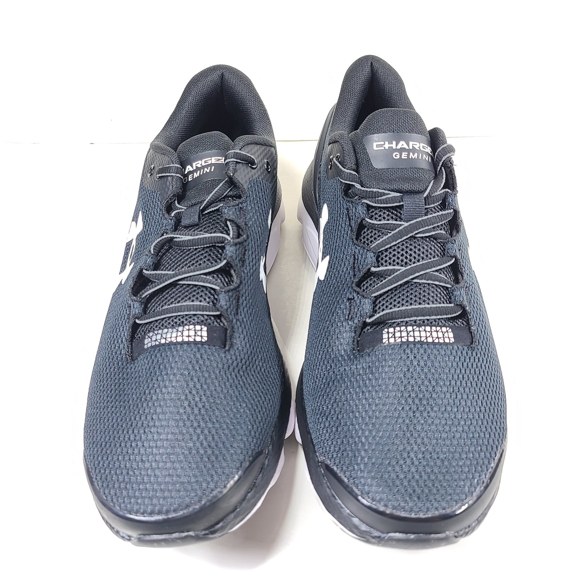 Black and white Under Armour Charged Gemini running shoes with branded sole and tongue detailing.