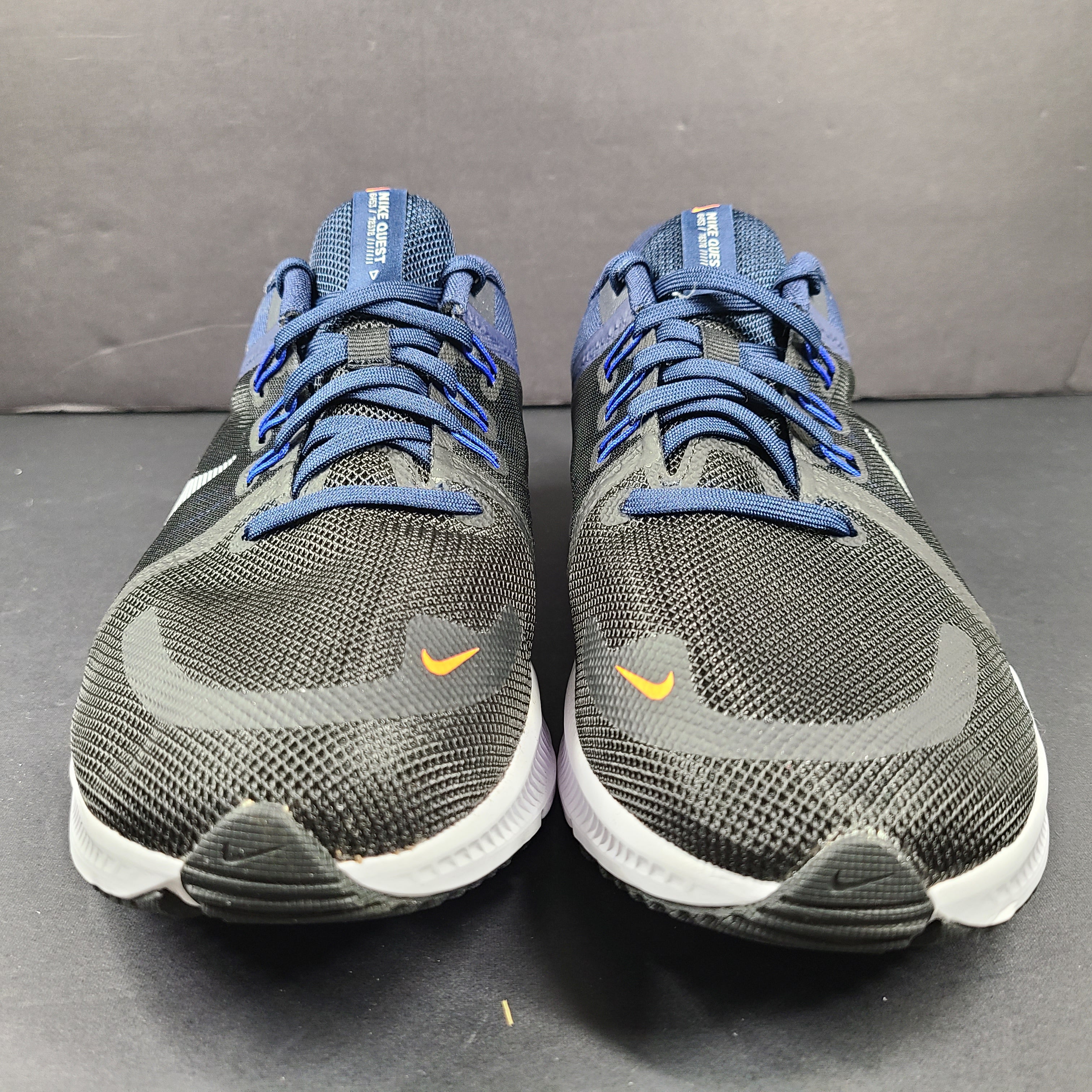Black, blue and orange Nike Quest 4 running shoes in US size 9 with breathable mesh upper and cushioned sole.