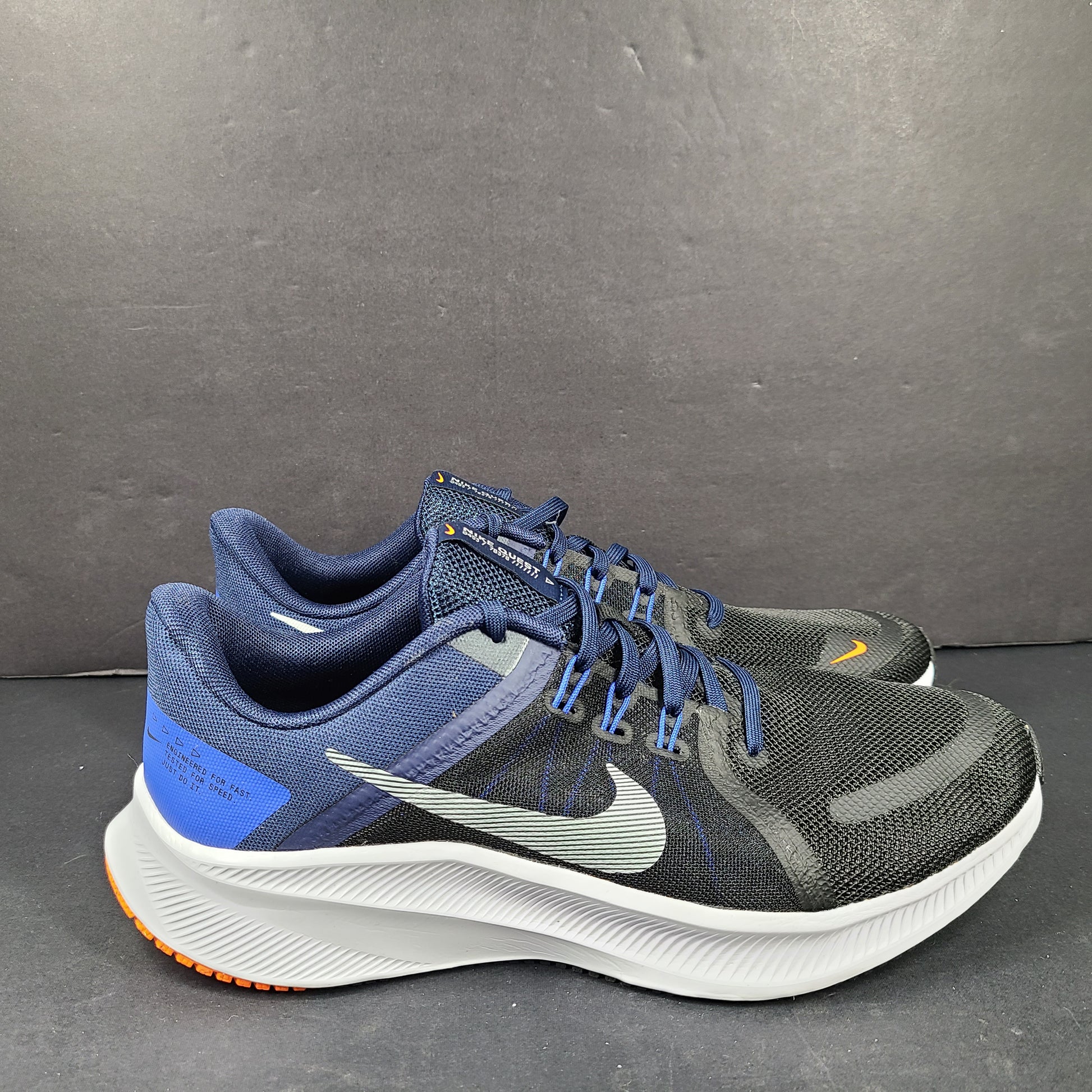 Black, blue and orange Nike Quest 4 running shoes in US size 9 with breathable mesh upper and cushioned sole.