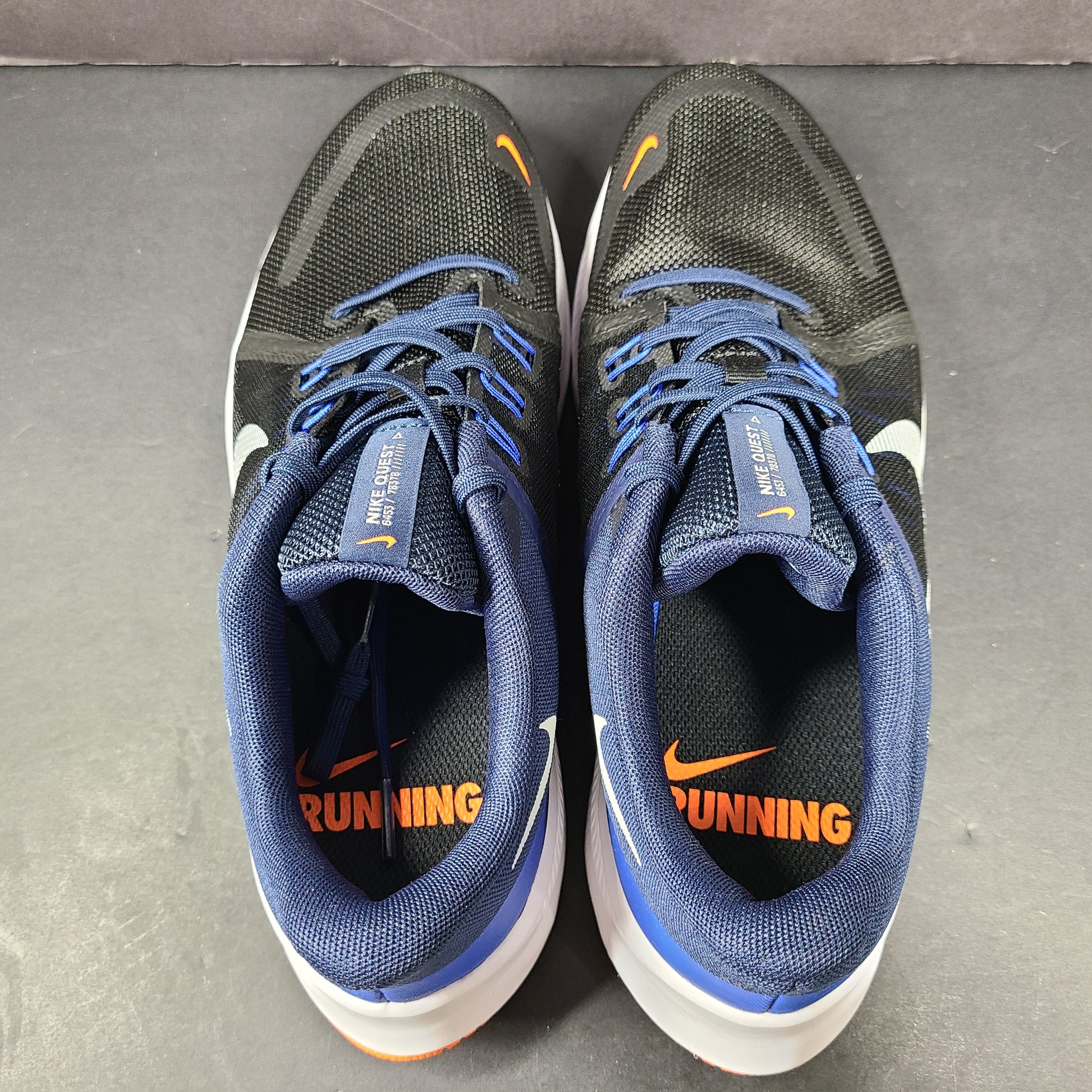 Black, blue and orange Nike Quest 4 running shoes in US size 9 with breathable mesh upper and cushioned sole.